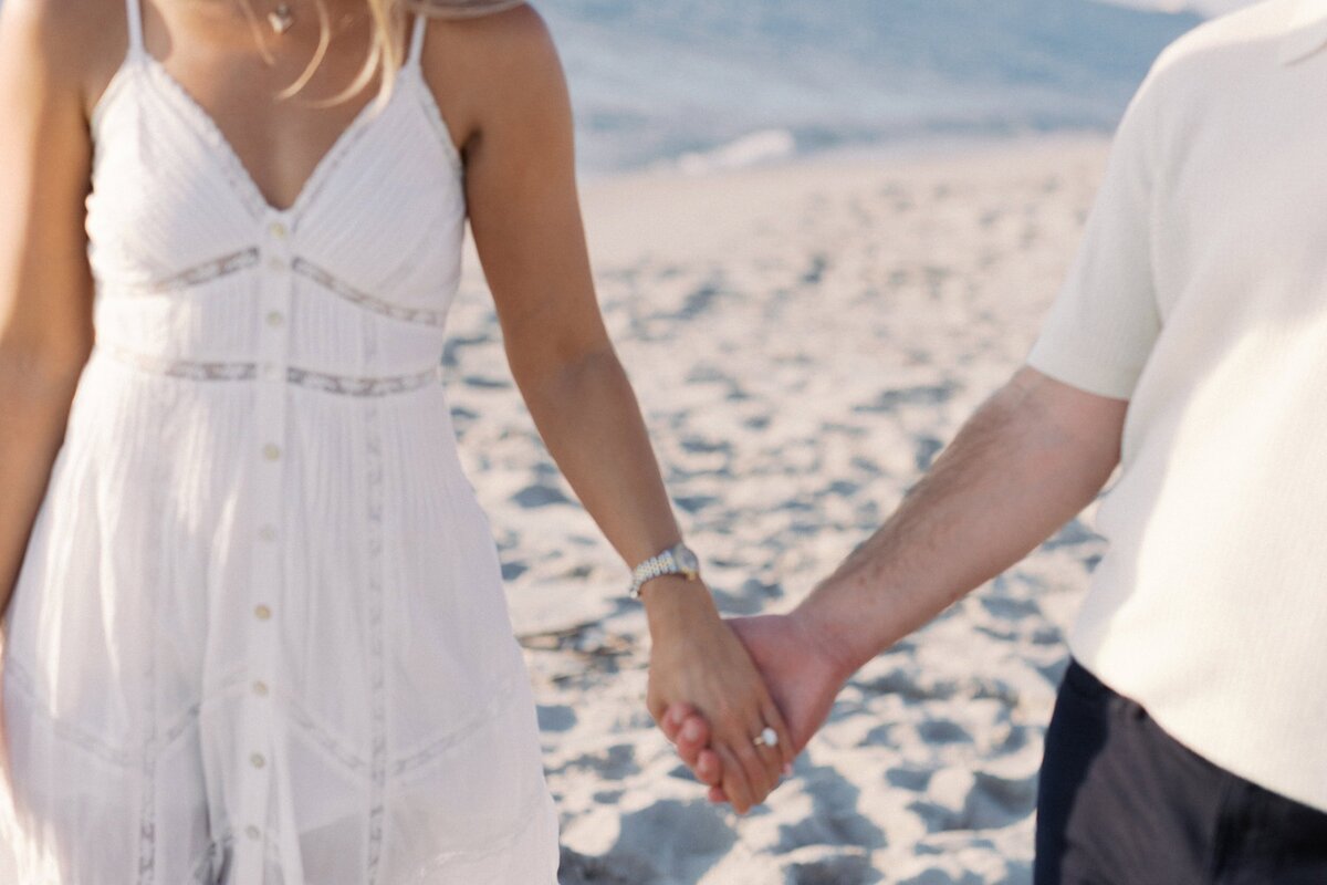 photo of couple's hands at the beach