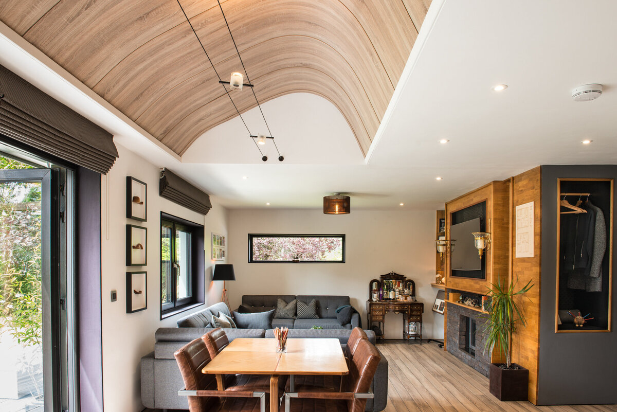 Bright open plan dining and living area with fireplace and coved wood ceiling