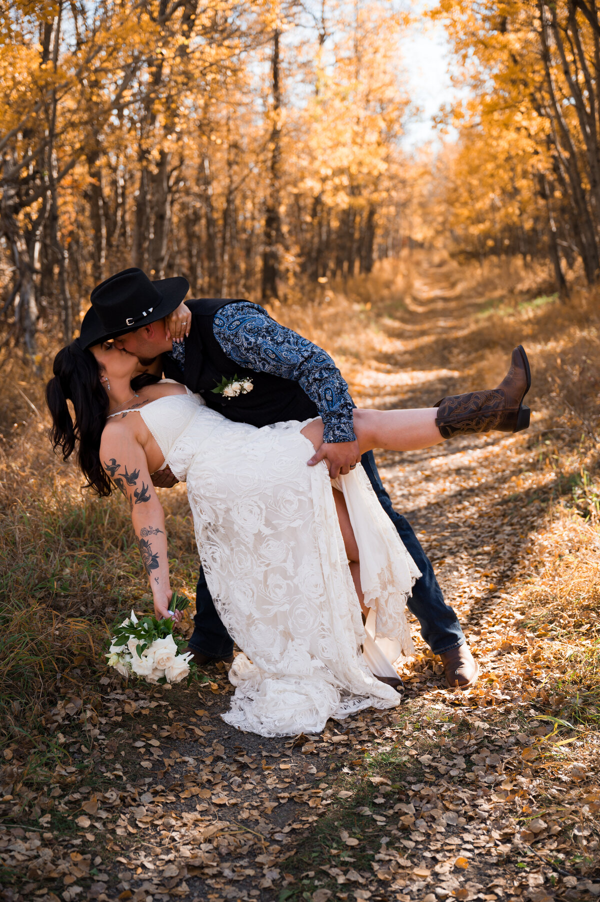 Western wedding portrait of a groom dipping his bride showing off cowboy boots and a cowboy hat