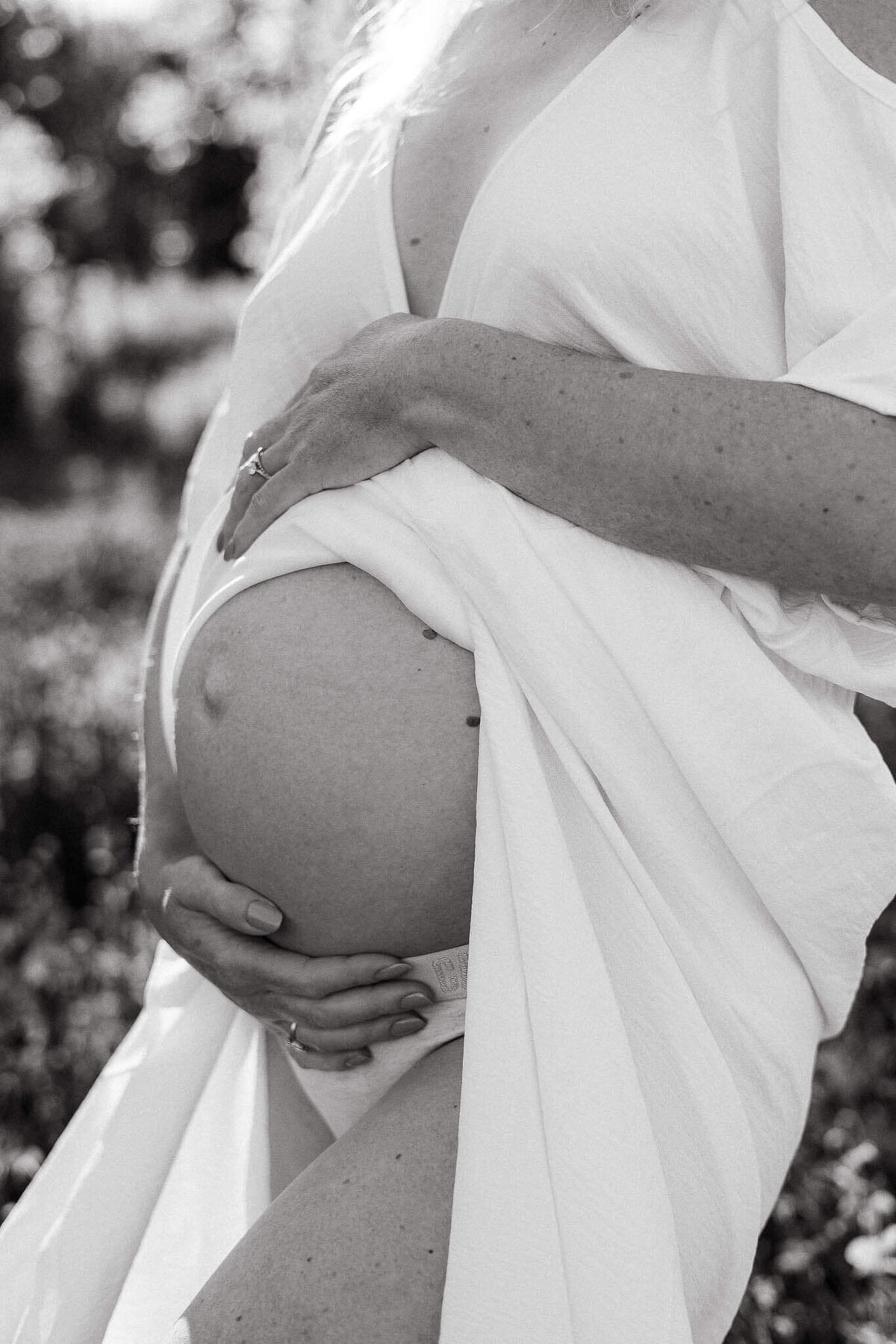 A black-and-white detail shot of a pregnant belly, highlighting the beauty of maternity photography in Cleveland.
