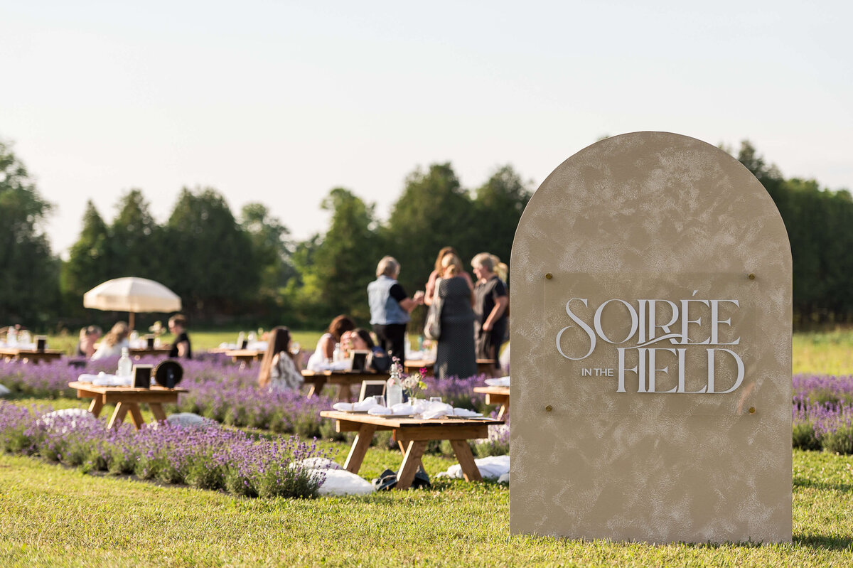 Signage of Soiree in the Field and guests in the background.  Captured by Ottawa Event Photographer JEMMAN Photography COMMERCIAL