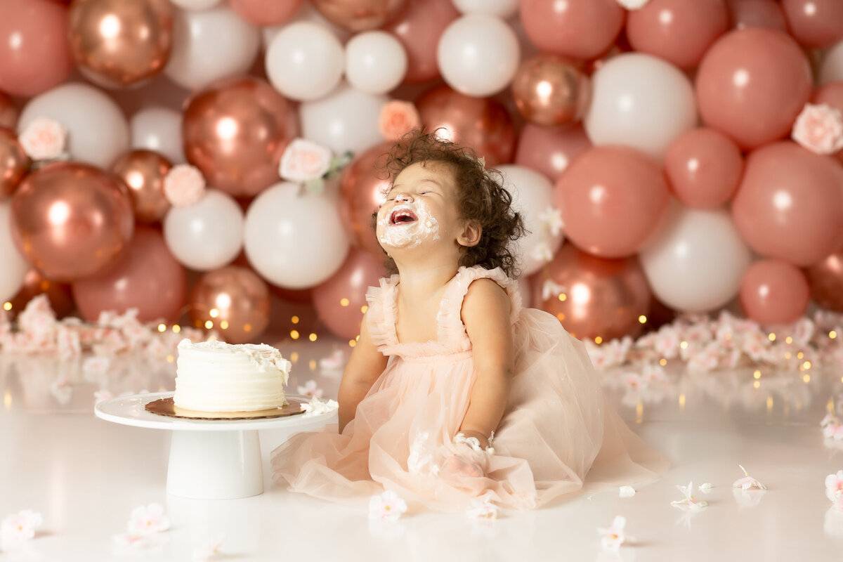 One year old Tampa baby enjoying a personalized luxury cake smash session with balloon and floral decorations