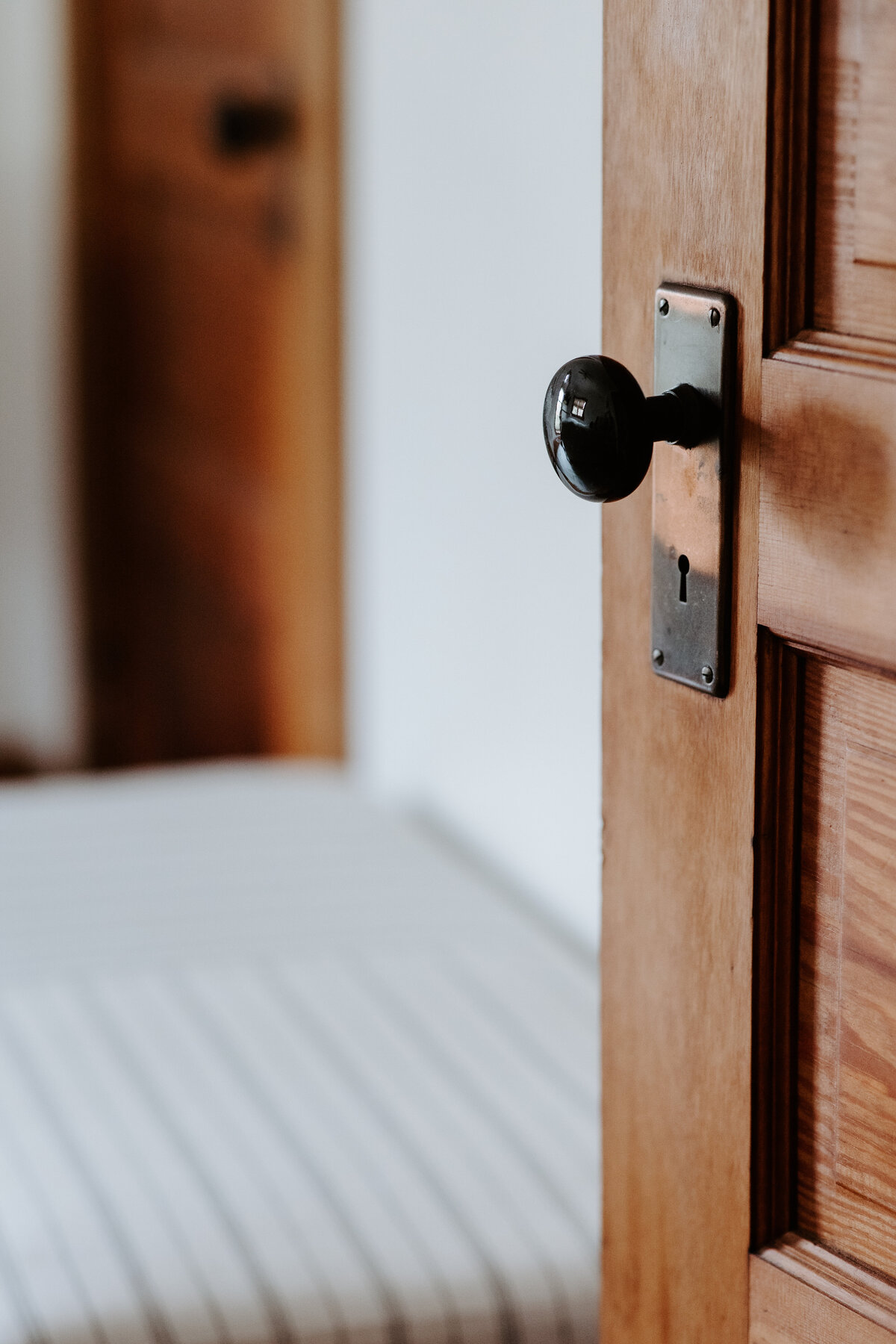 an image of an open vintage door with old door handle and striped McGee and Co Threshold by Target ottoman in the modern farmhouse overnight accommodations at Willowbrook wedding venue