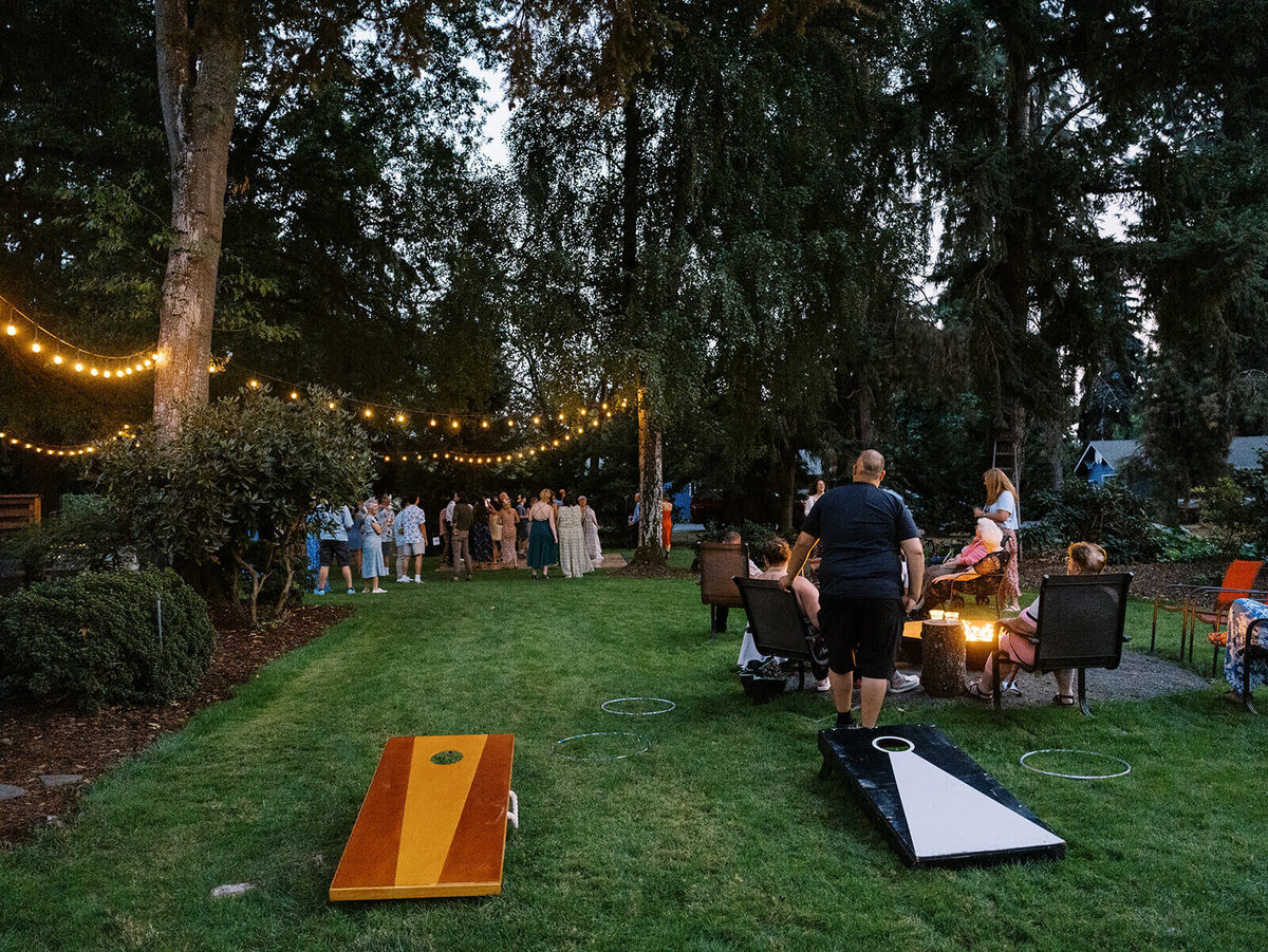 Backyard wedding reception with bistro lights and games pictured from afar. 