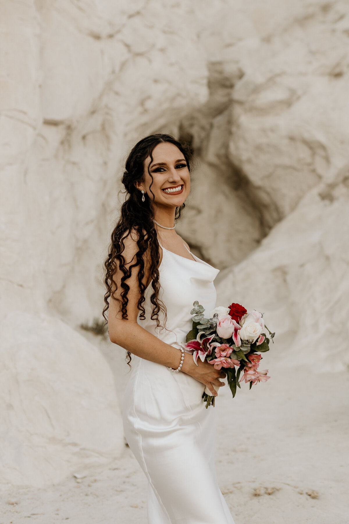 portrait of a bride standing in front of a massive white rock in New Mexico