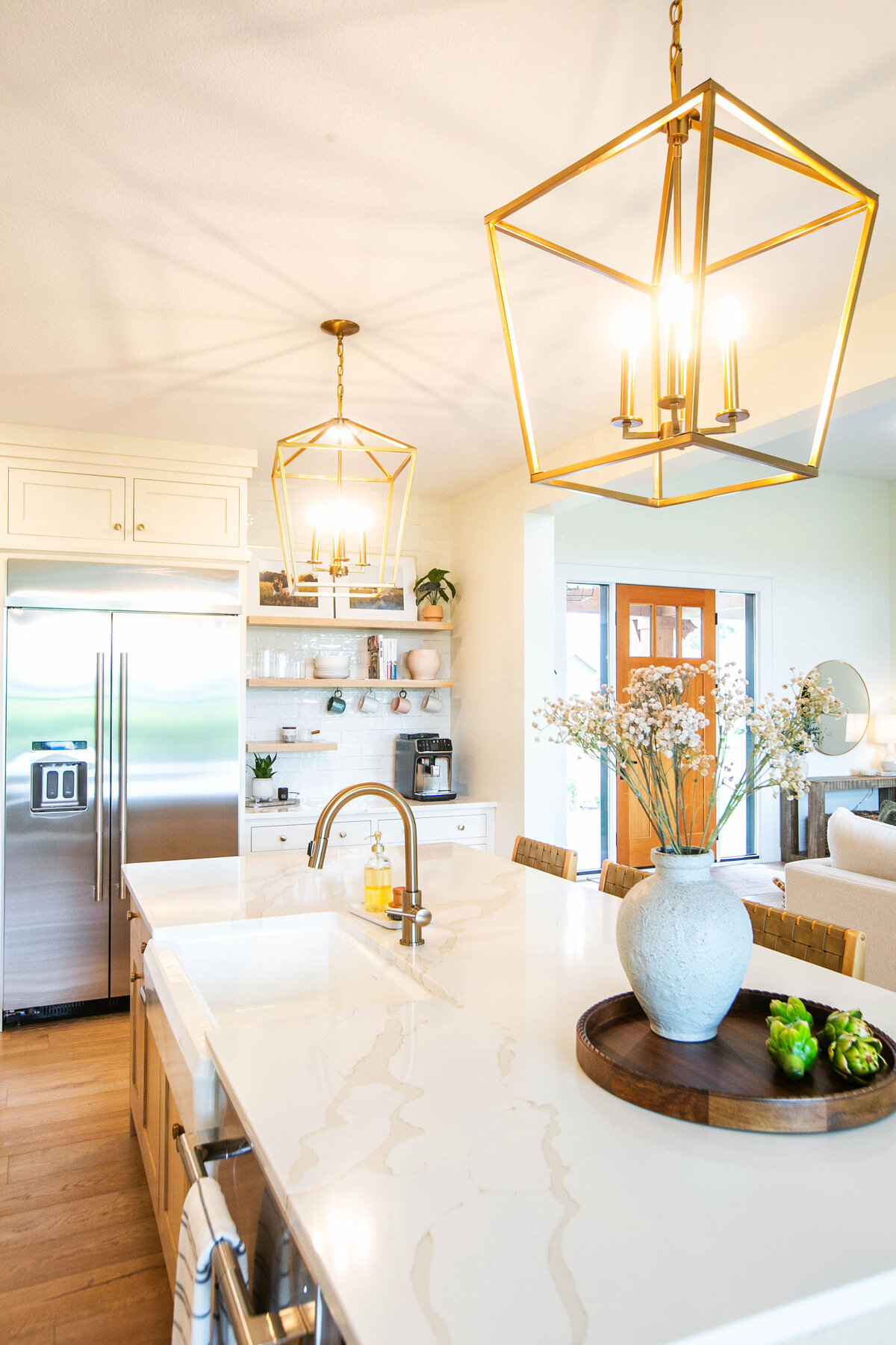 Open kitchen with white cabinets, large island, and quartz countertops in an Otsego custom home