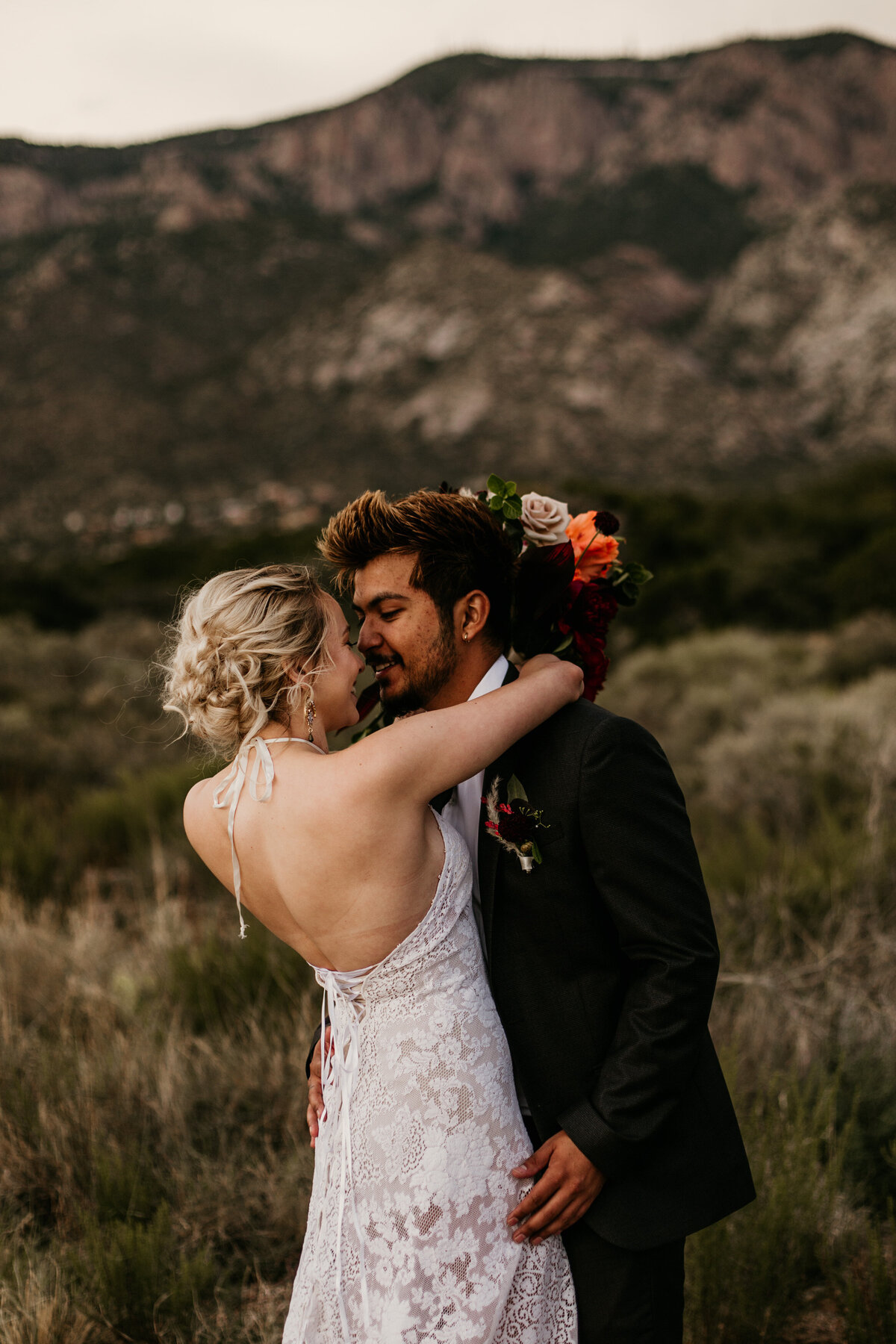 bride and groom about to kiss in desert