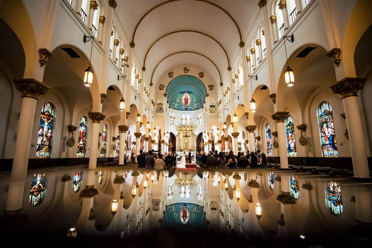 Wide angle reflection photograph of the inside of the Basilica of the Sacred Heart of Jesus in Atlanta during a wedding ceremony by Charlotte wedding photographers DeLong Photography