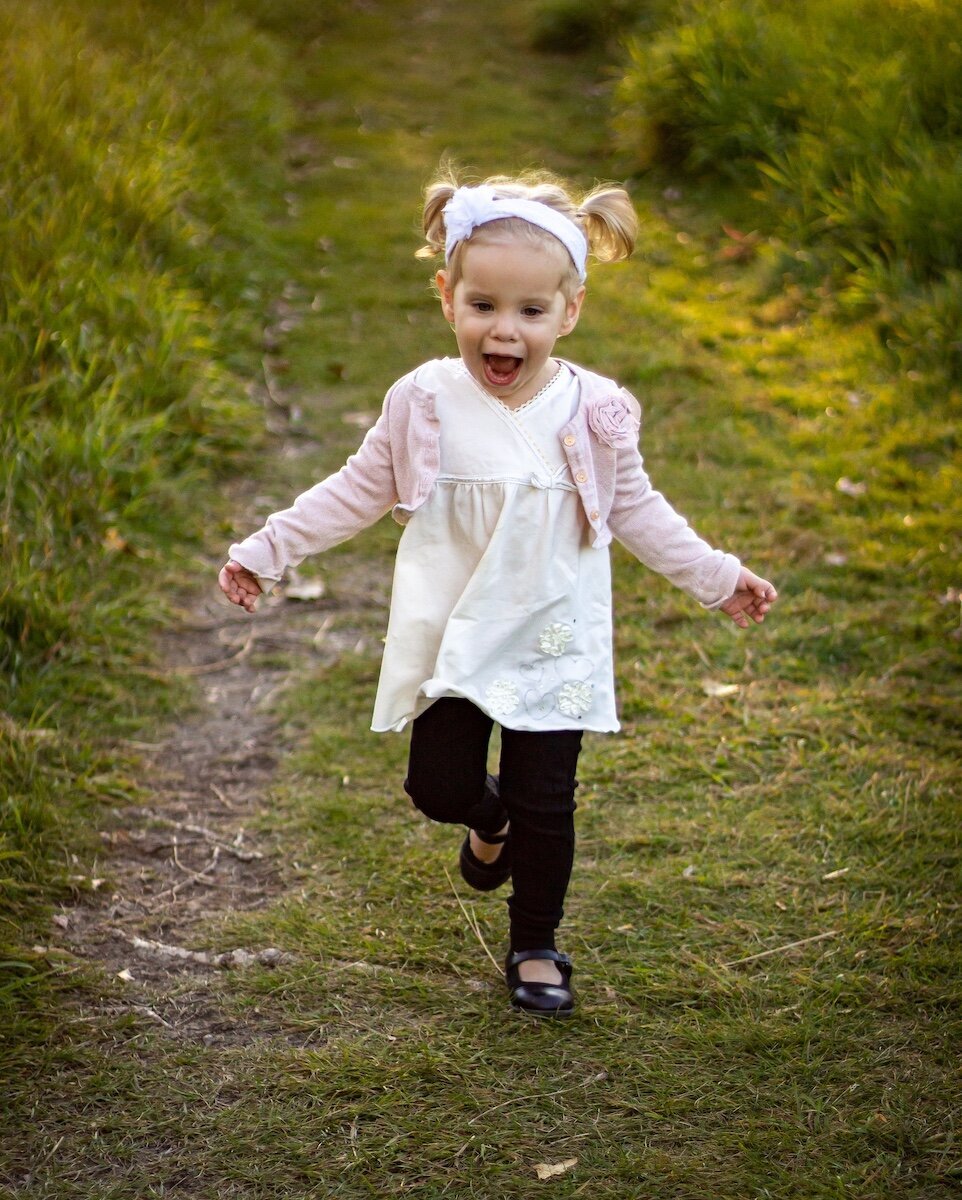 little girl with pigtails runs down a dirt road near Edmonton