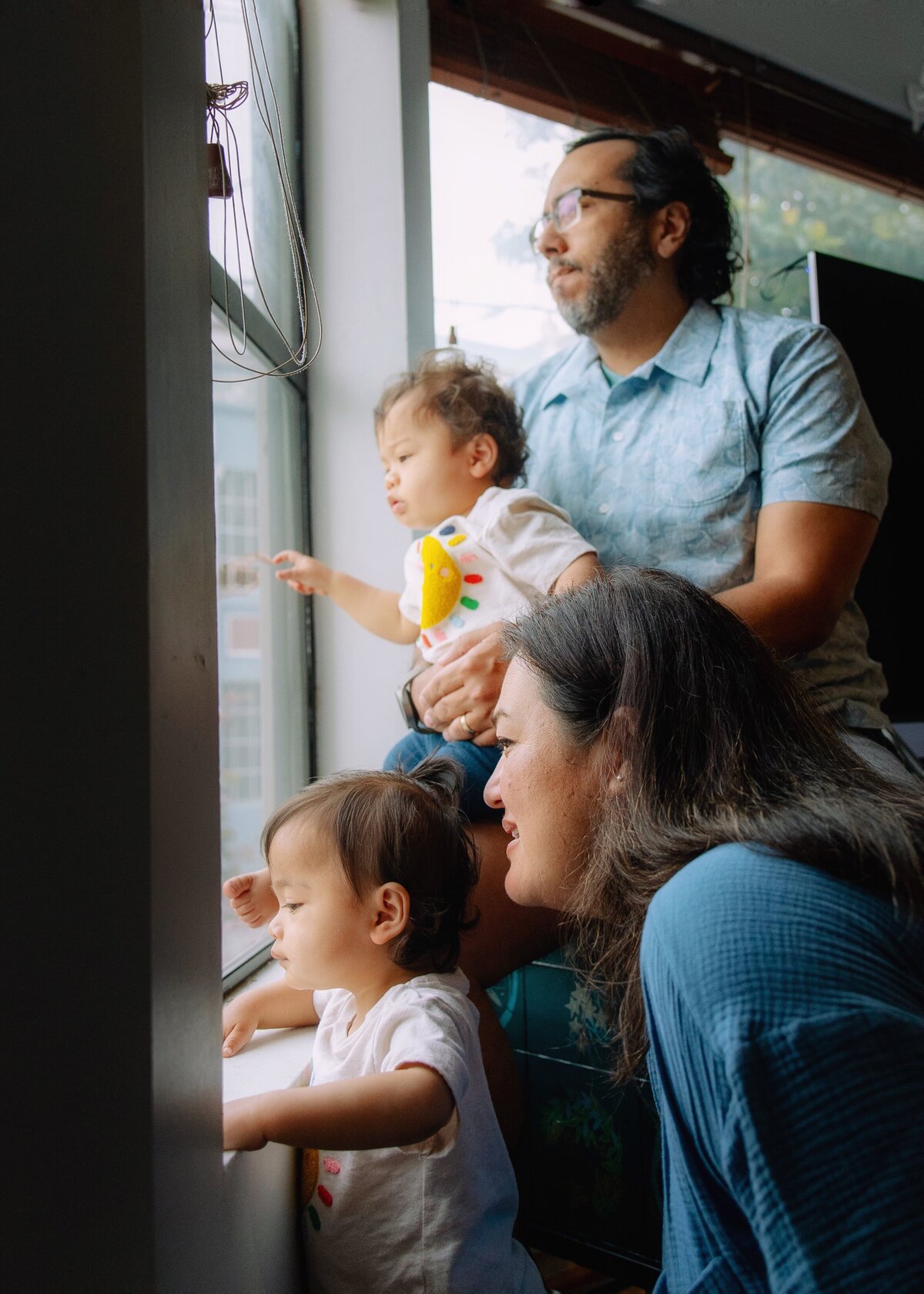 Family of four looks out the window at their house