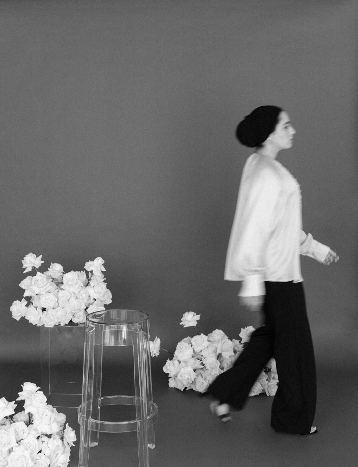 movement brand photography, florist, walking among white roses with dark backdrop