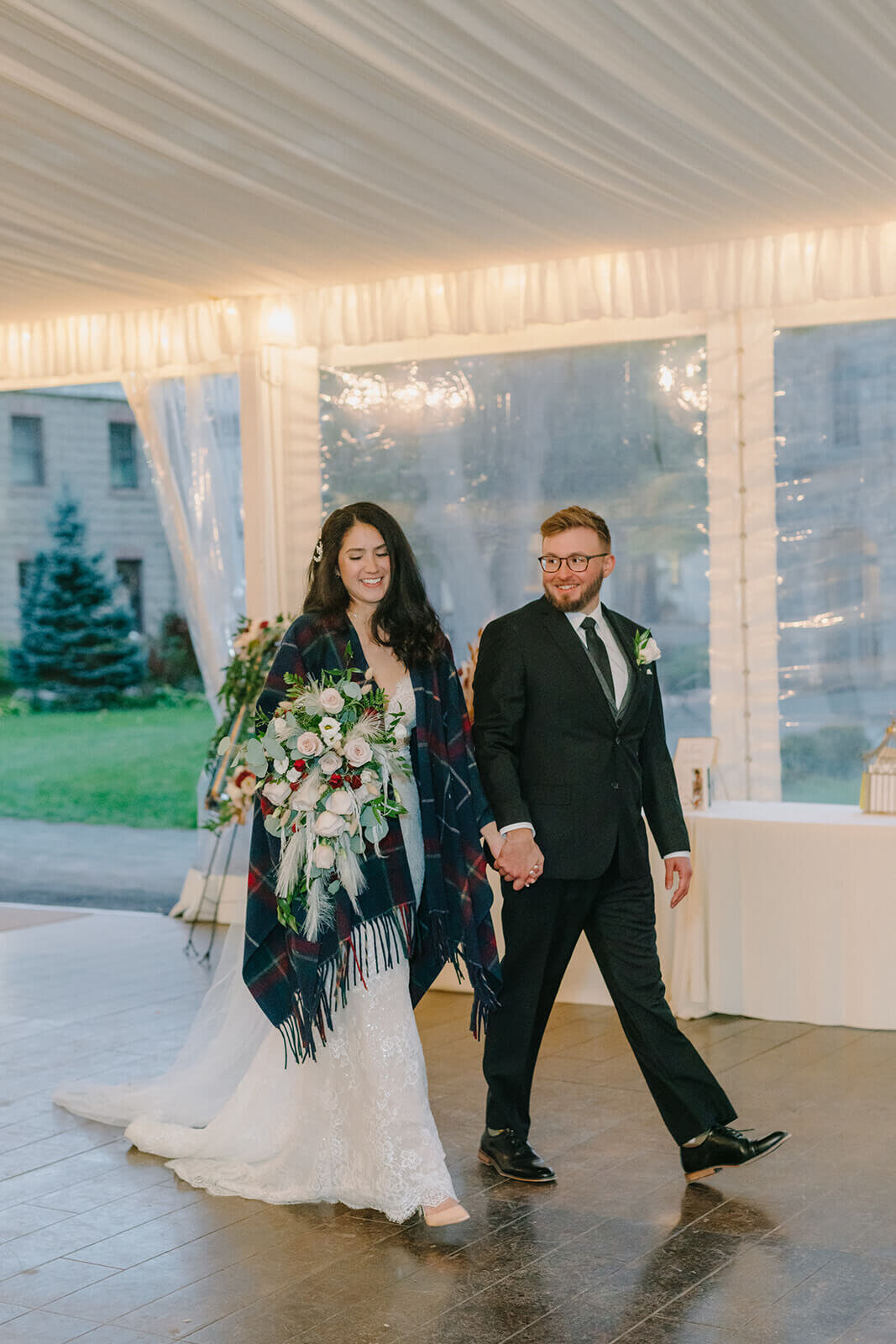 Bride walking aong inside marquee with groom
