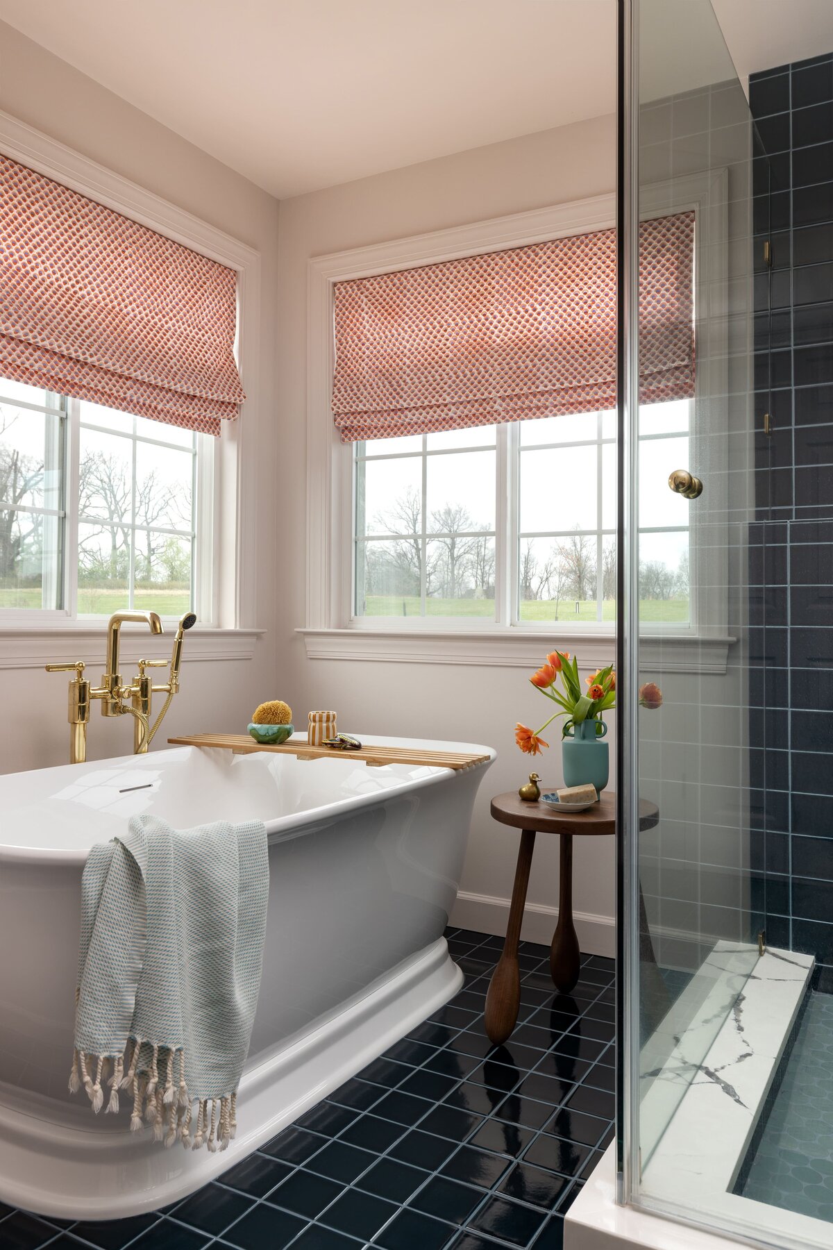 Freestanding tub with brass fixtures and blue-green tile floor in a Northern Virginia primary bathroom remodel