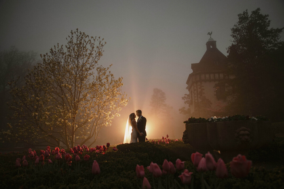 A couple at their wedding backlit by the setting sun surrounded by fog