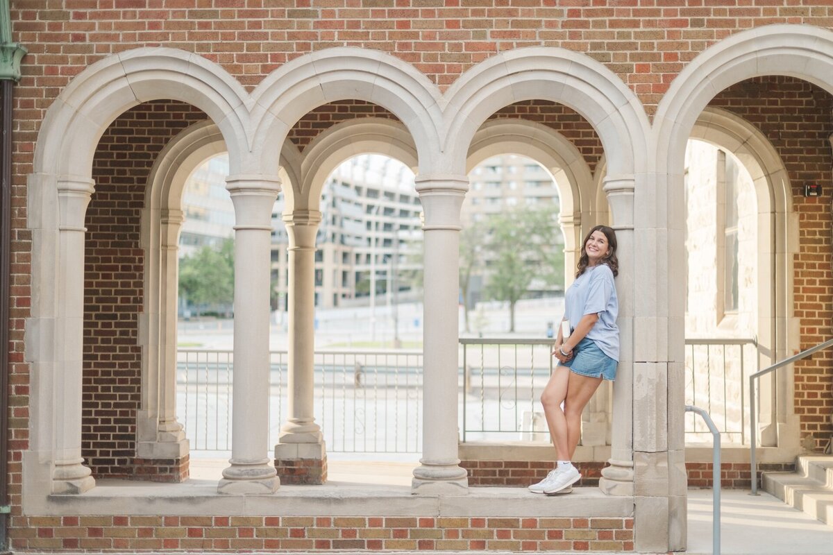 a girl standing with her back to a grand pillar