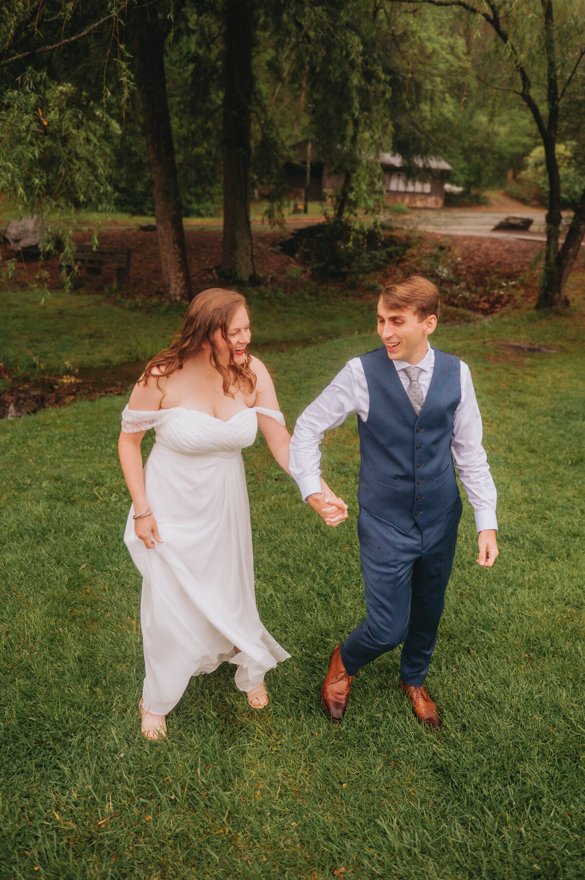 A couple holds hands while walking in the grass smiling