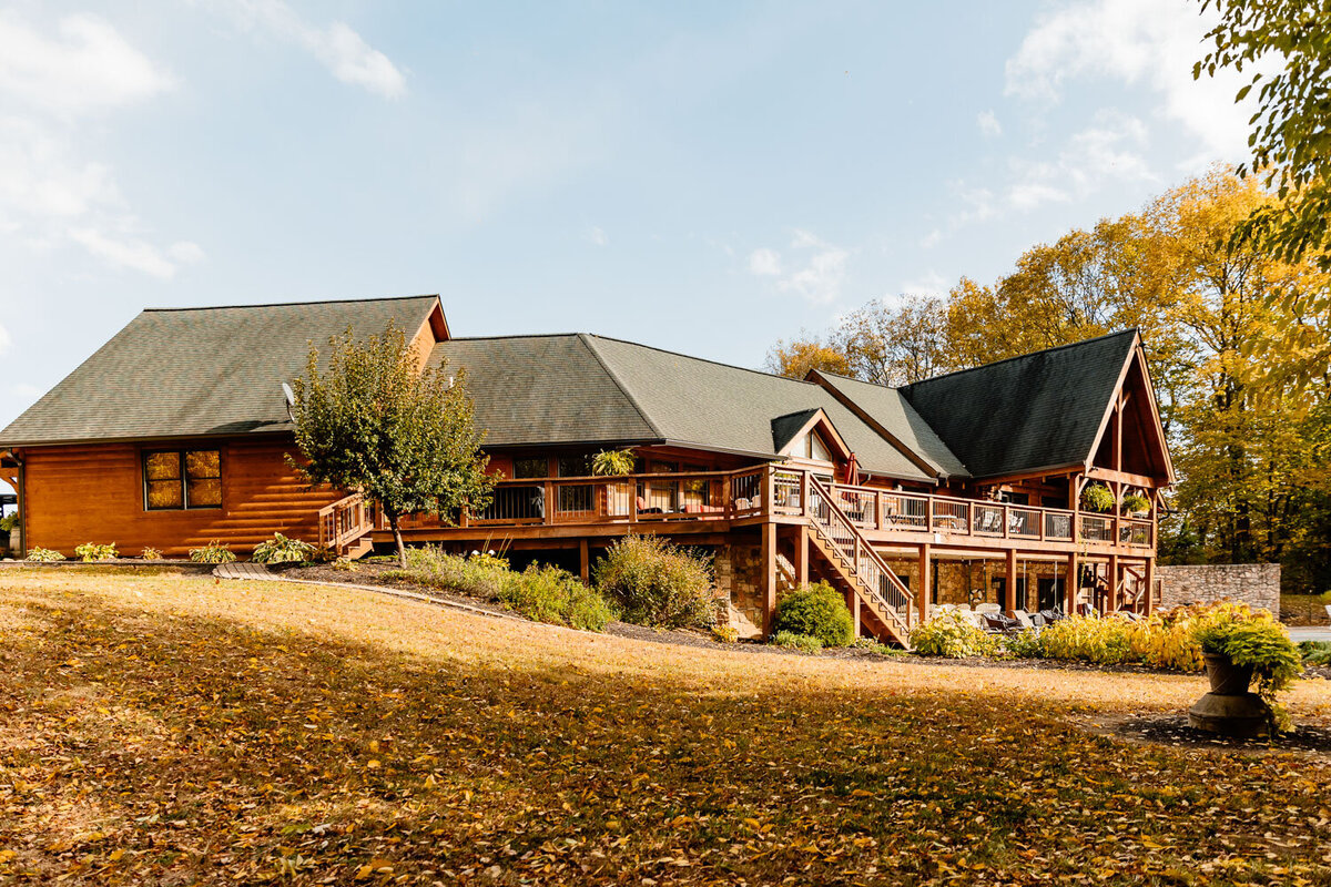 Charming cabin-style venue with a green lawn and autumn trees in the background