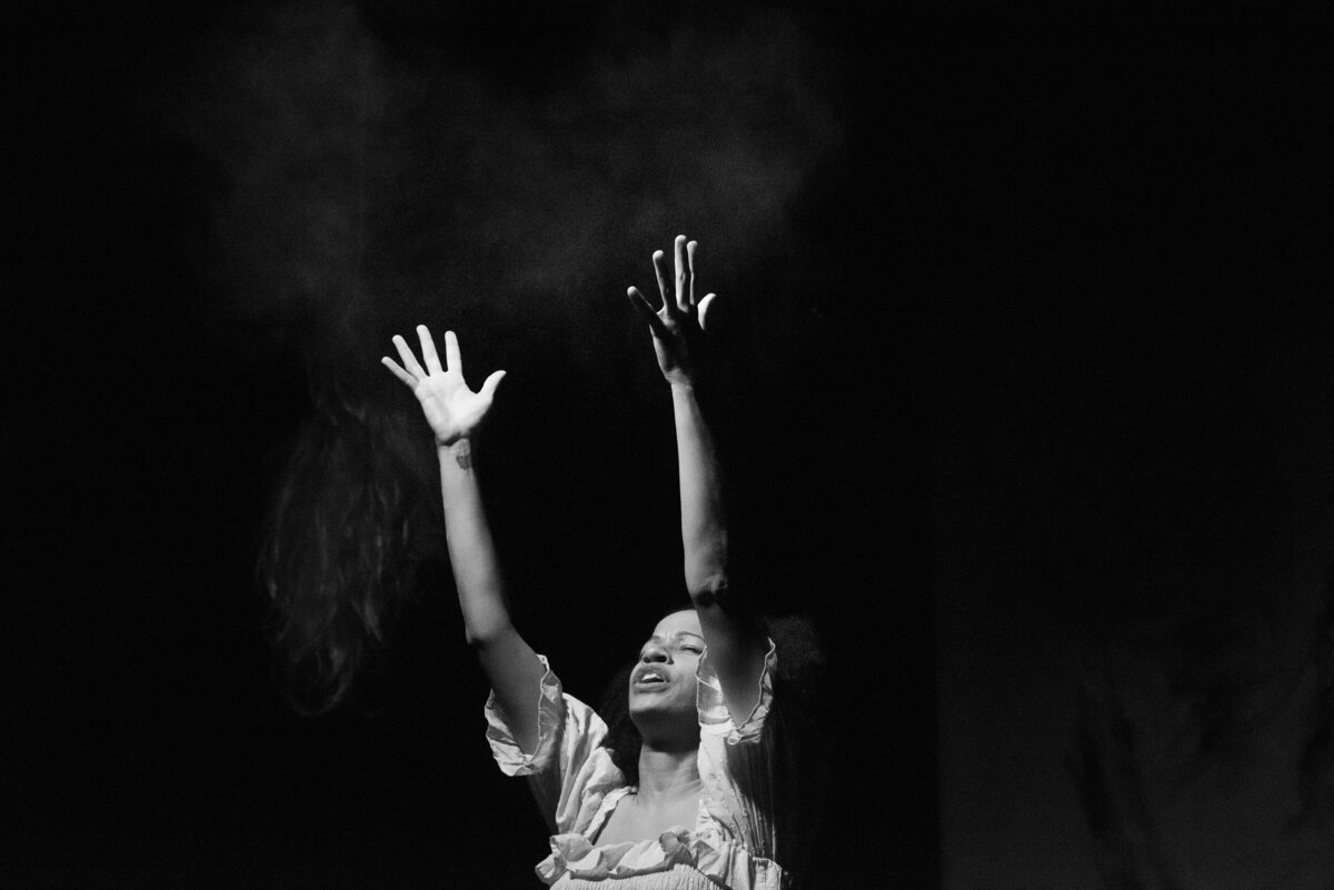 Black and white photo of a person reaching their hands up