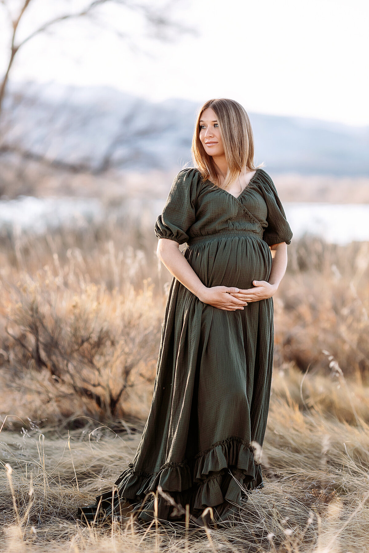pretty spring sunset with mama in a field in a olive gown for her maternity photos in fort collins co