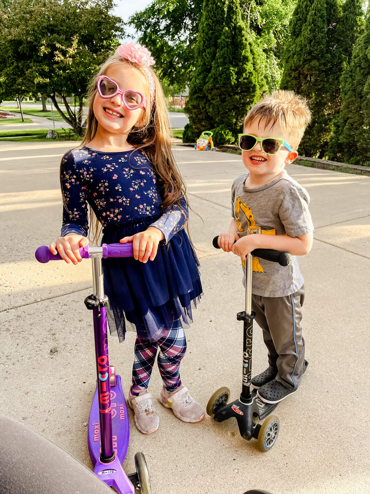 A brother and sister wearing sunglasses and riding a scooter near Naperville, IL.