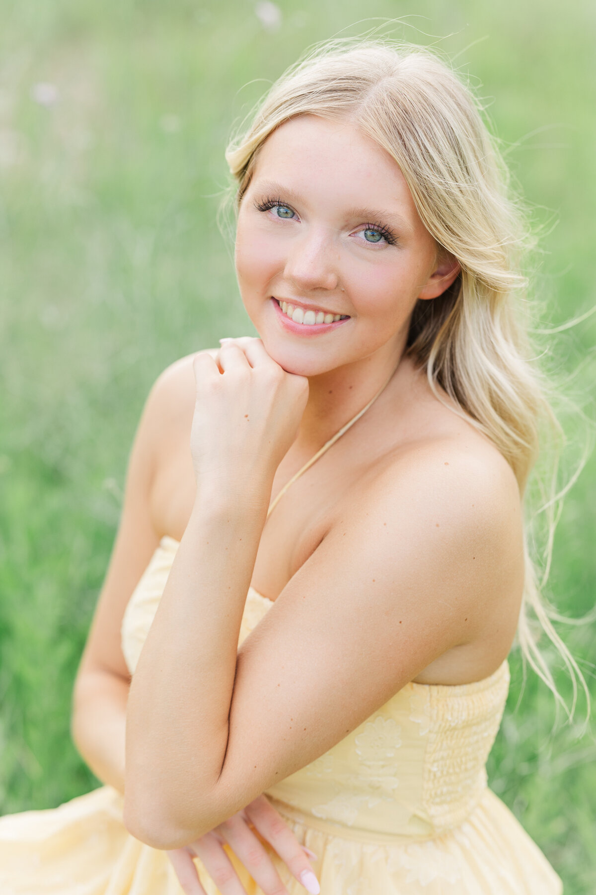 A radiant senior girl poses in a yellow dress surrounded by soft green grass at Arbor Hills Nature Preserve. A timeless, natural-light senior photo captured by a Plano-based photographer serving DFW and surrounding suburbs.