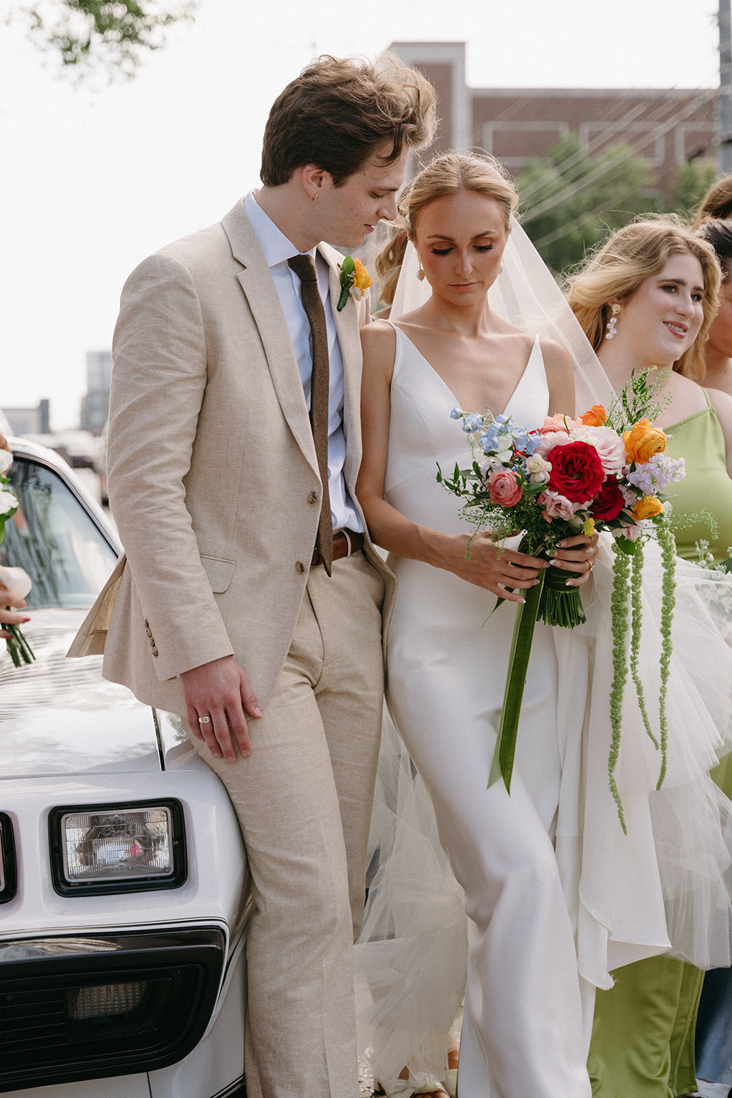 Candid photo of couple standing side by side in front of Corvet for bridal party photos. 