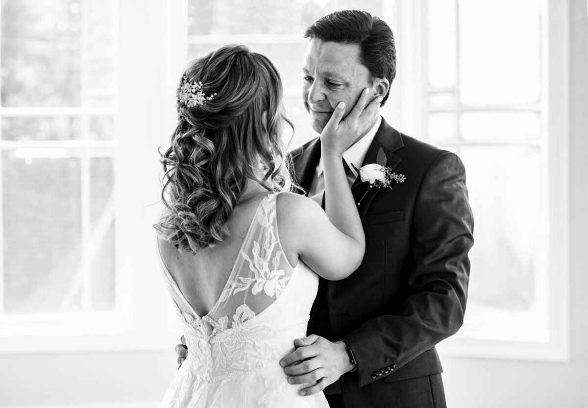 Black-and-white-photograph-of-a-bride-touching-her-crying-groom's-face-during-a-first-look-at-Pine-Island-Country-Club-in-Charlotte