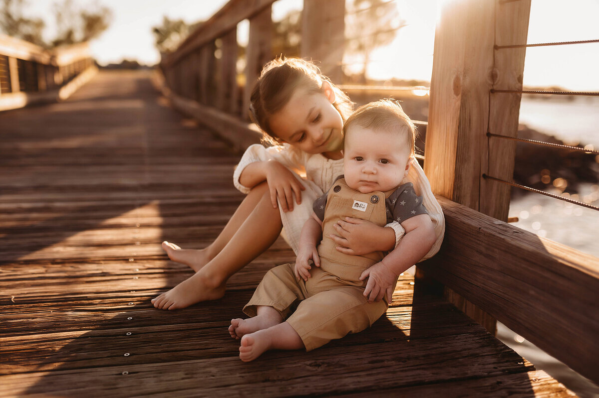 Big sister embraces her new baby brother during Family Portrait Session in Charleston, South Carolina.