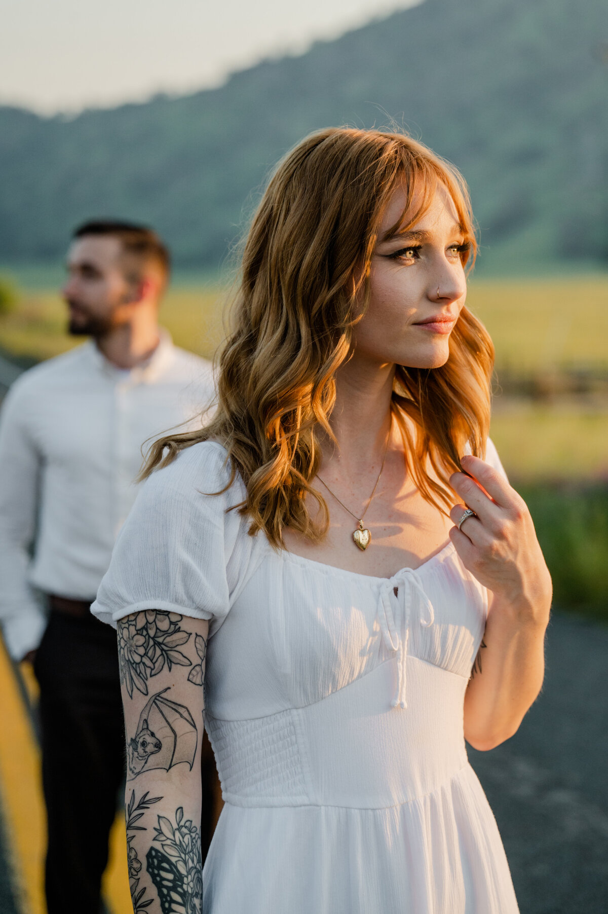 Bride-to-be framed in golden light, engagement ring catching the sun as her fingers brush through her hair.