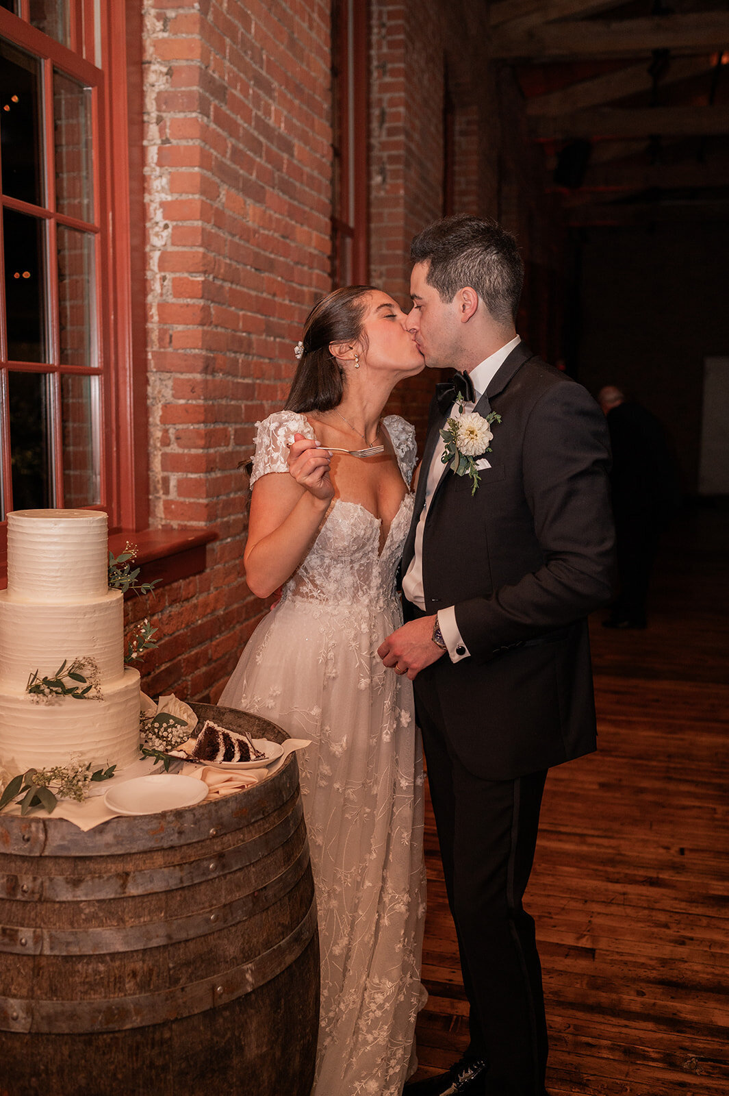 couple celebrates with a kiss after cutting cake during city winery reception