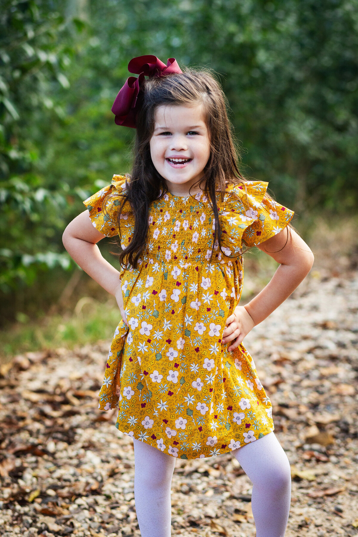 little girl in yellow dress proudly smiling