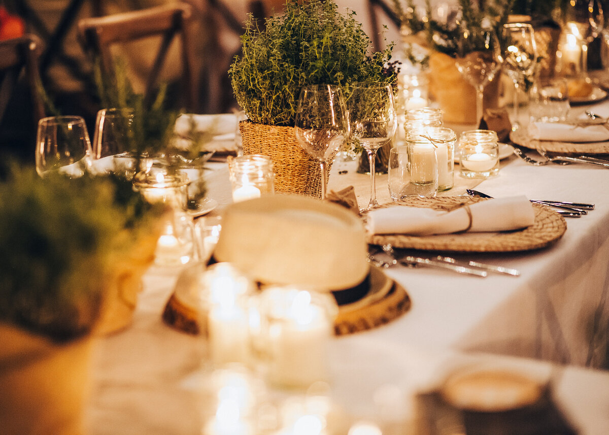 A rustic wedding table set up with herbs in pots for an elegant outdoor wedding.
