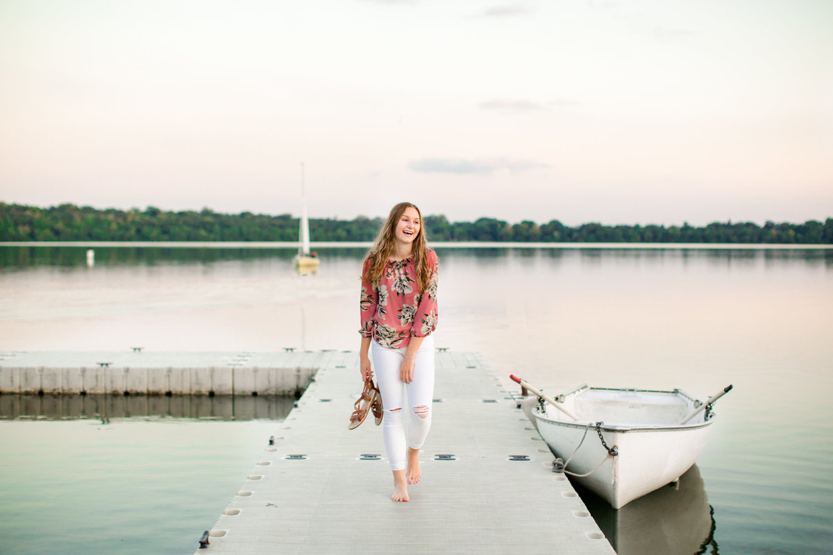 girl walks down docks of lake harriet for senior portraits minneapolis minnesota