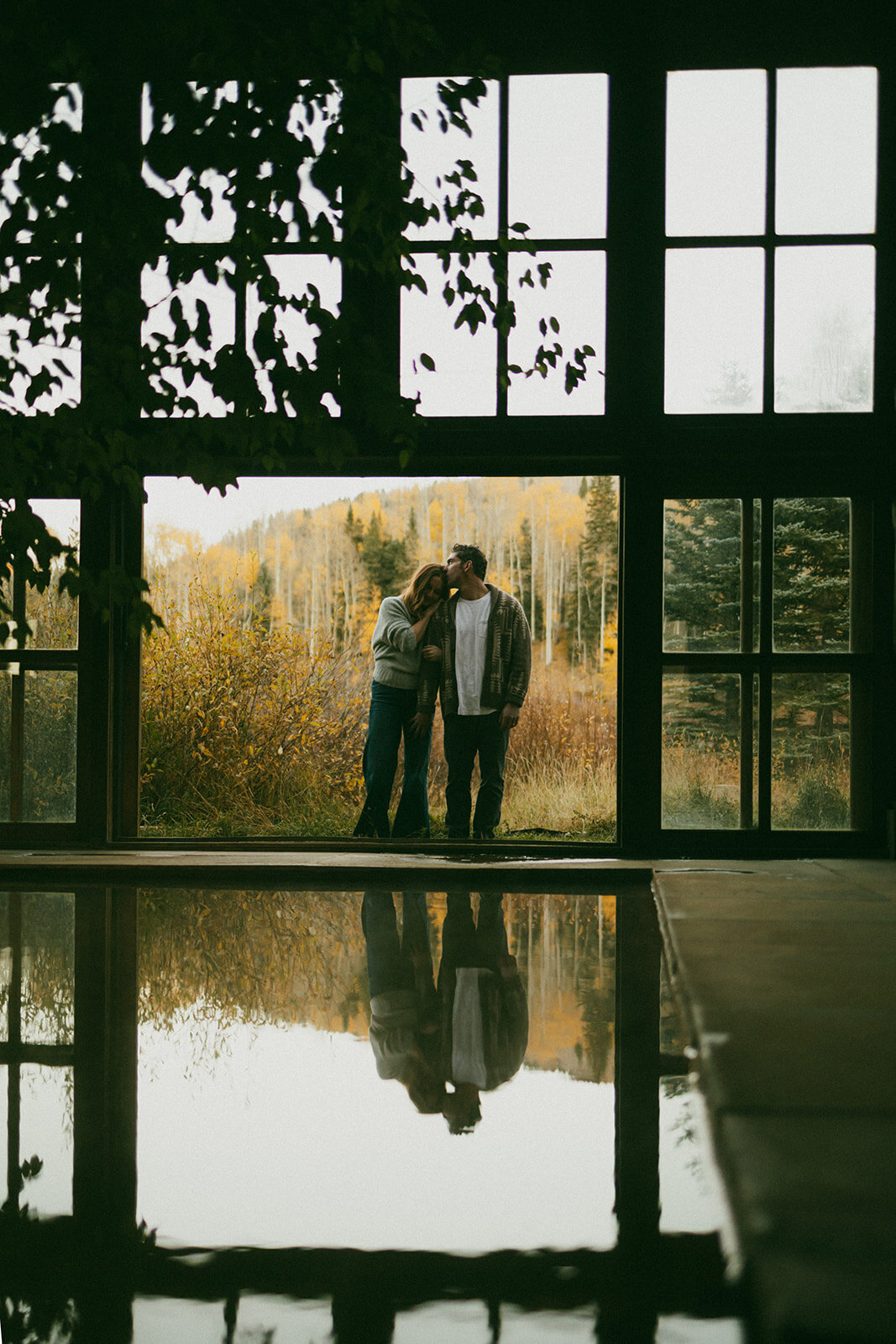 couple holding onto eachother near water outside of window