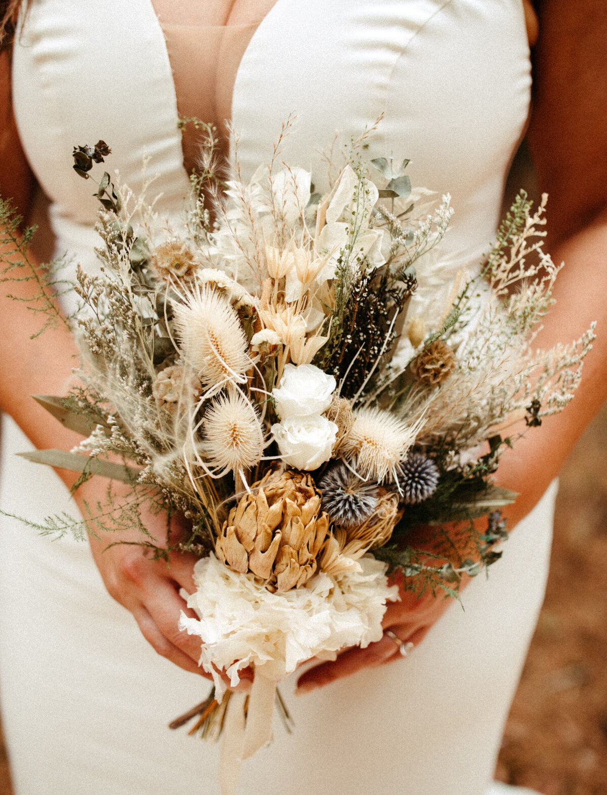 Close up of bride holding dried floral bouquet with dried flowers
