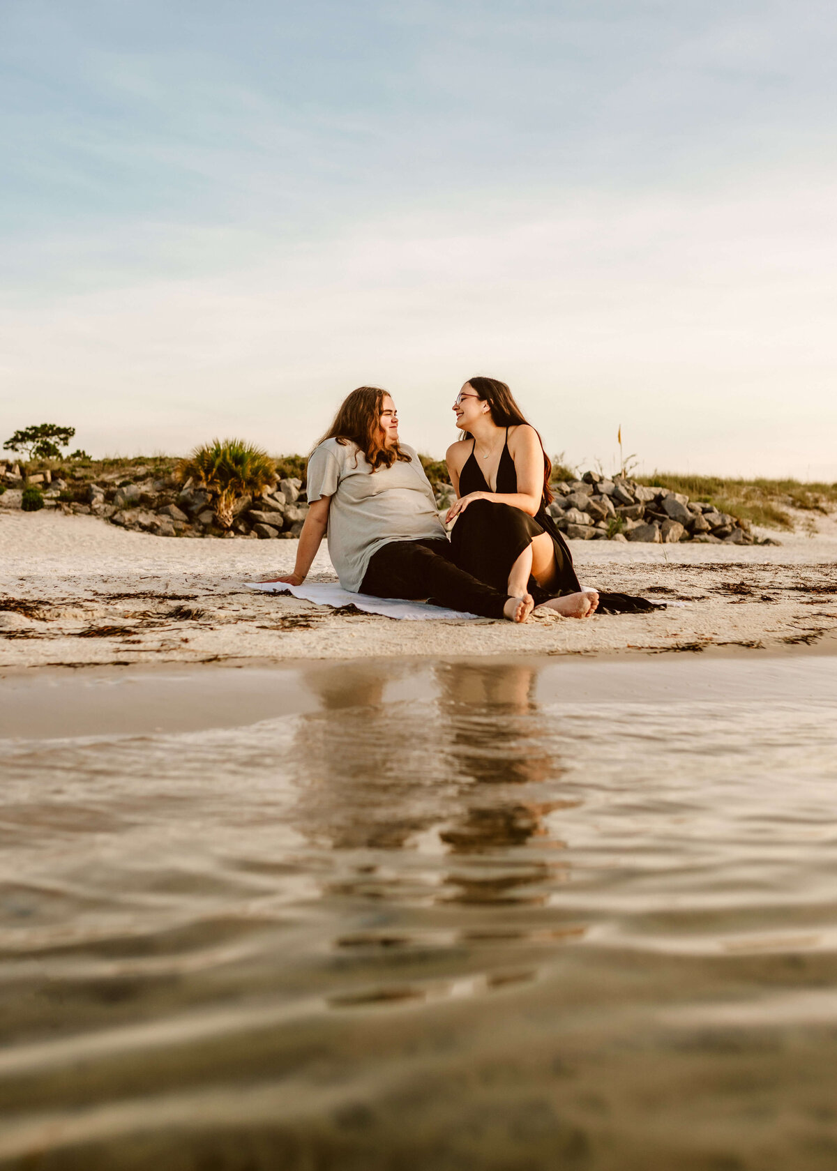 young lesbian couple relaxes on beach in panama city florida