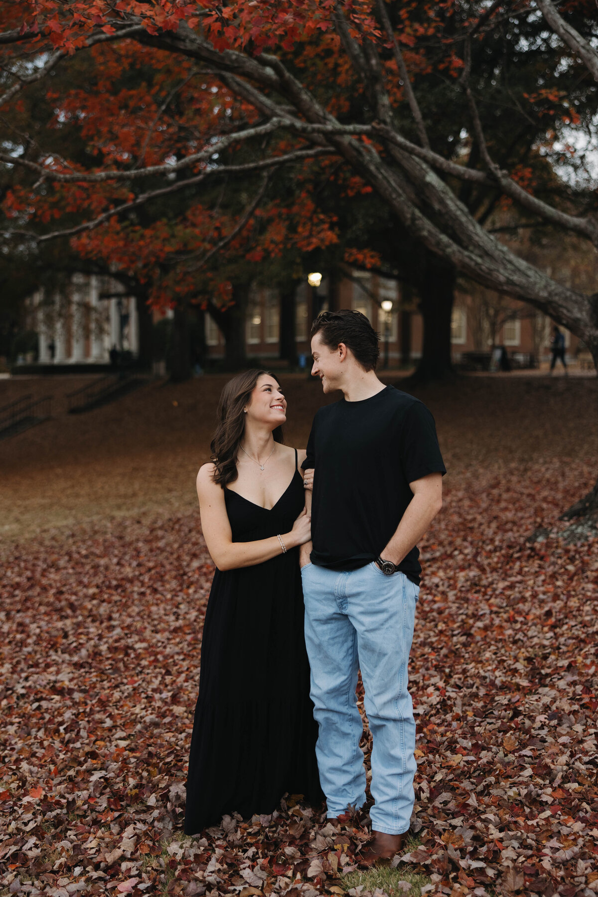 engaged couple looking at each other in the fall foliage