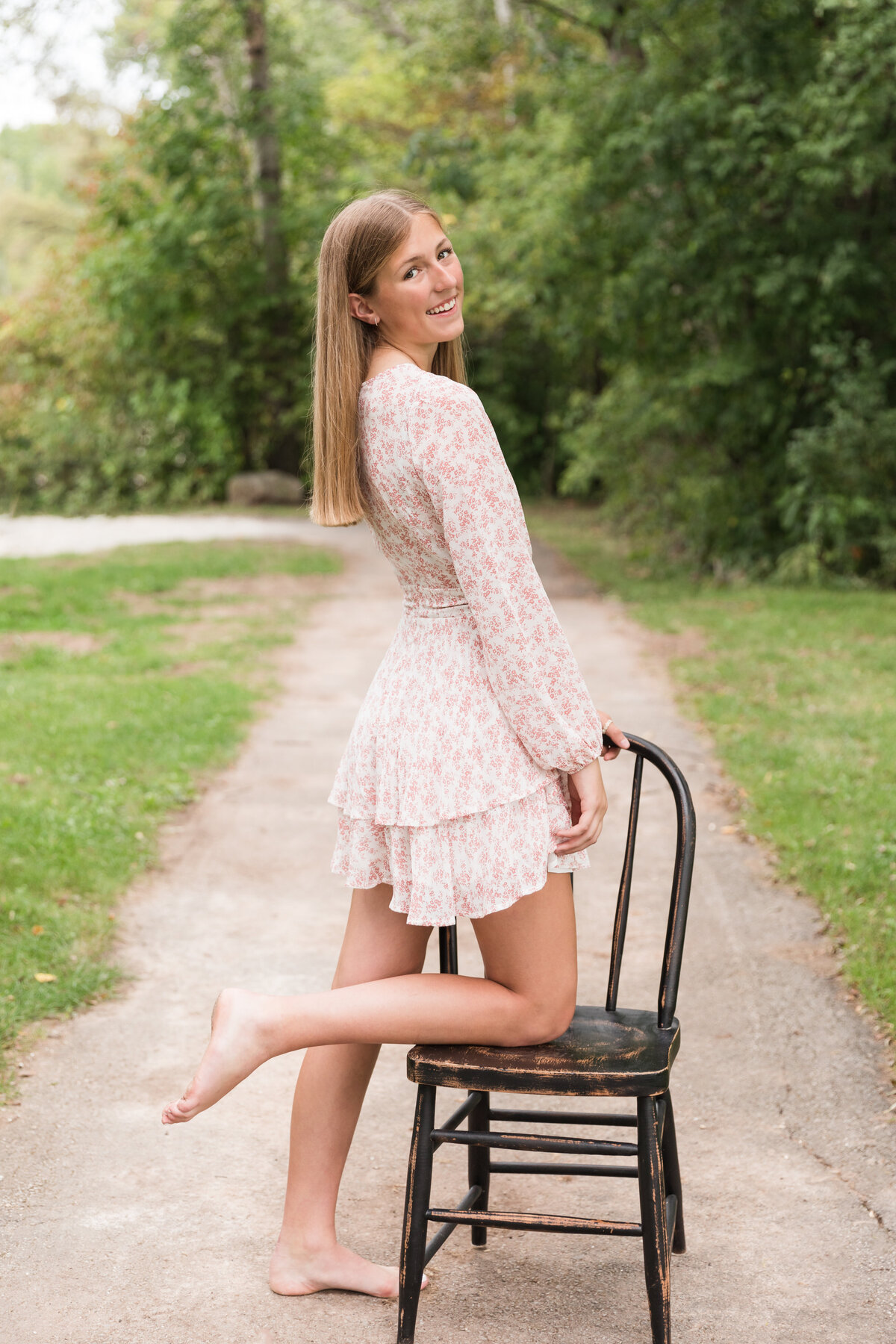 Senior girl kneeling on a chair smiling at the camera