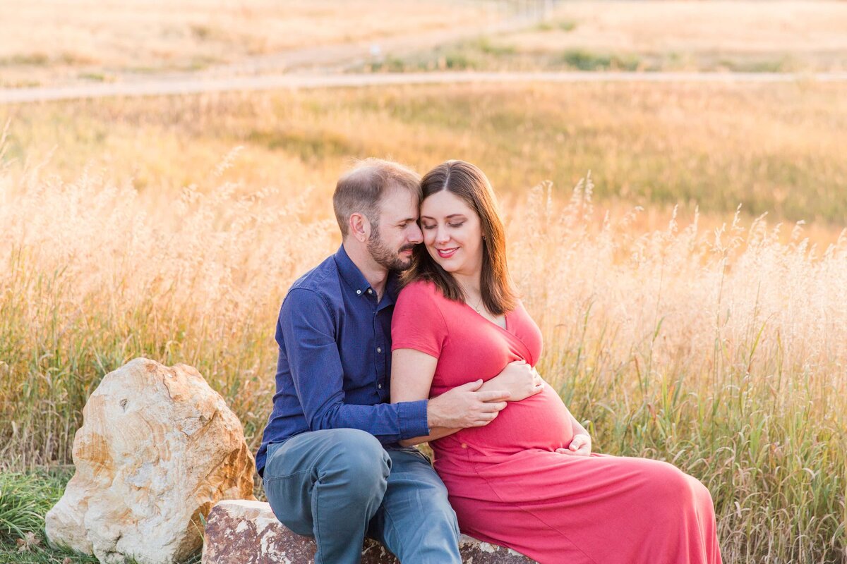 couple snuggles while sitting on rock in Arvada, Co