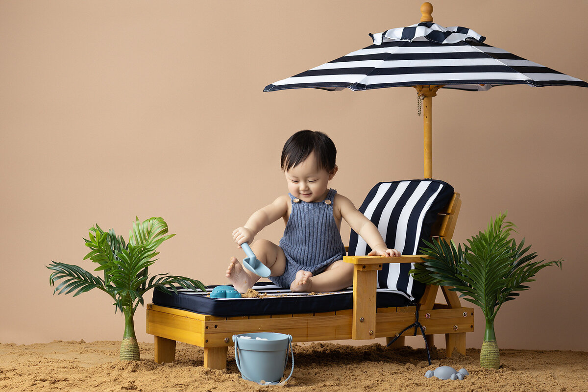 Dallas baby milestone photographer capturing a baby playing with a toy in the sand.