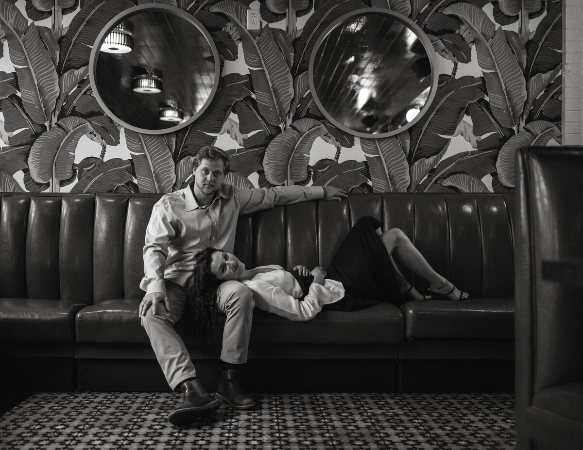 Couple sits on diner booth during their engagement session in Richmond Virginia, in black and white