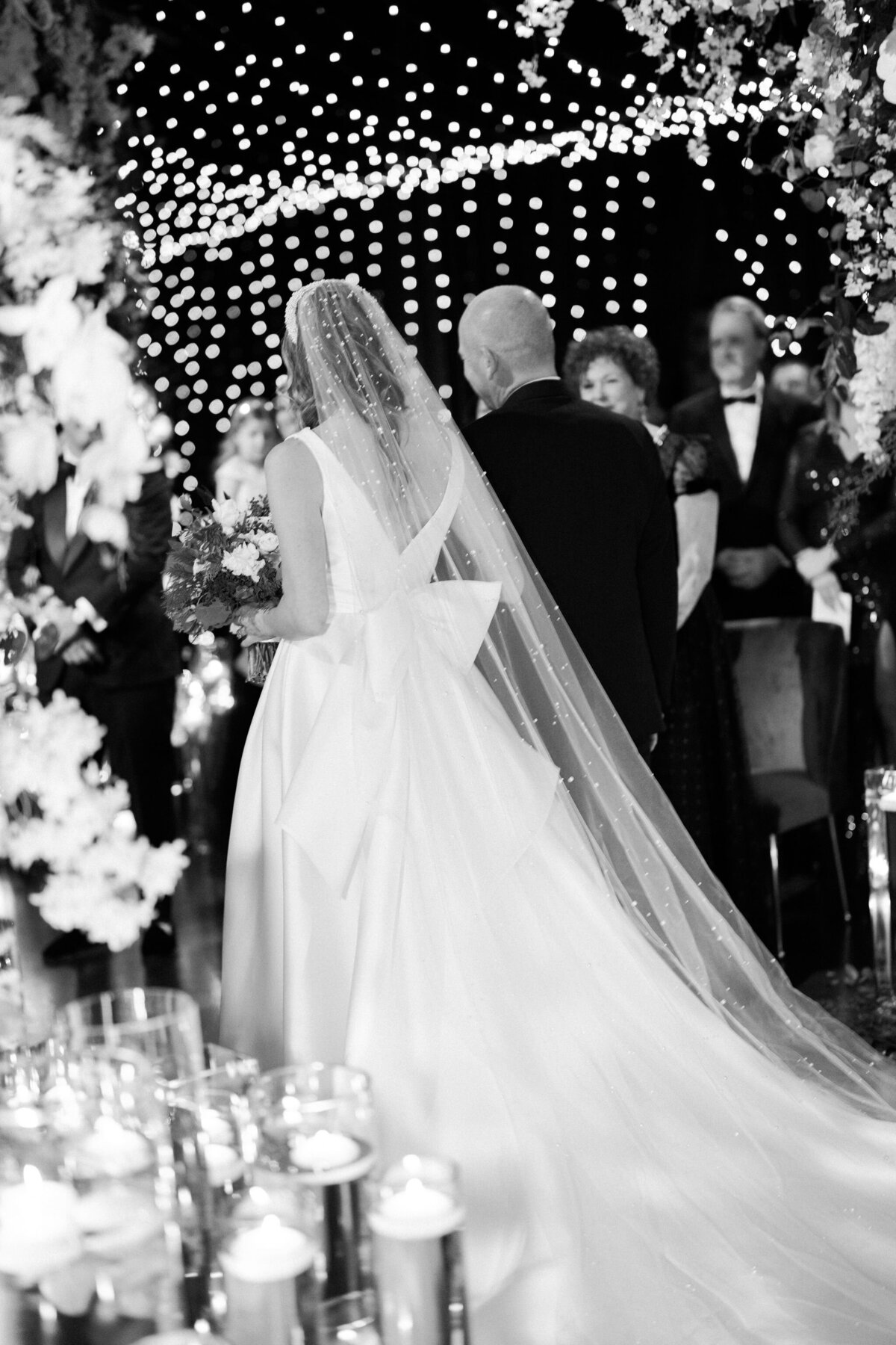 A black and white photo of the bride and father of the bride walking down the aisle. 