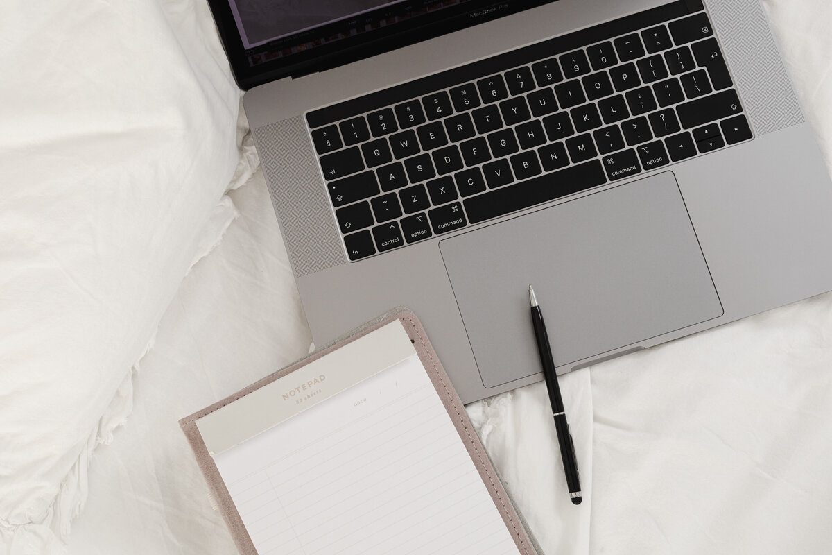 kaboompics_working-with-a-laptop-in-bed-white-cotton-bedding-blank-notebook-pen-28939