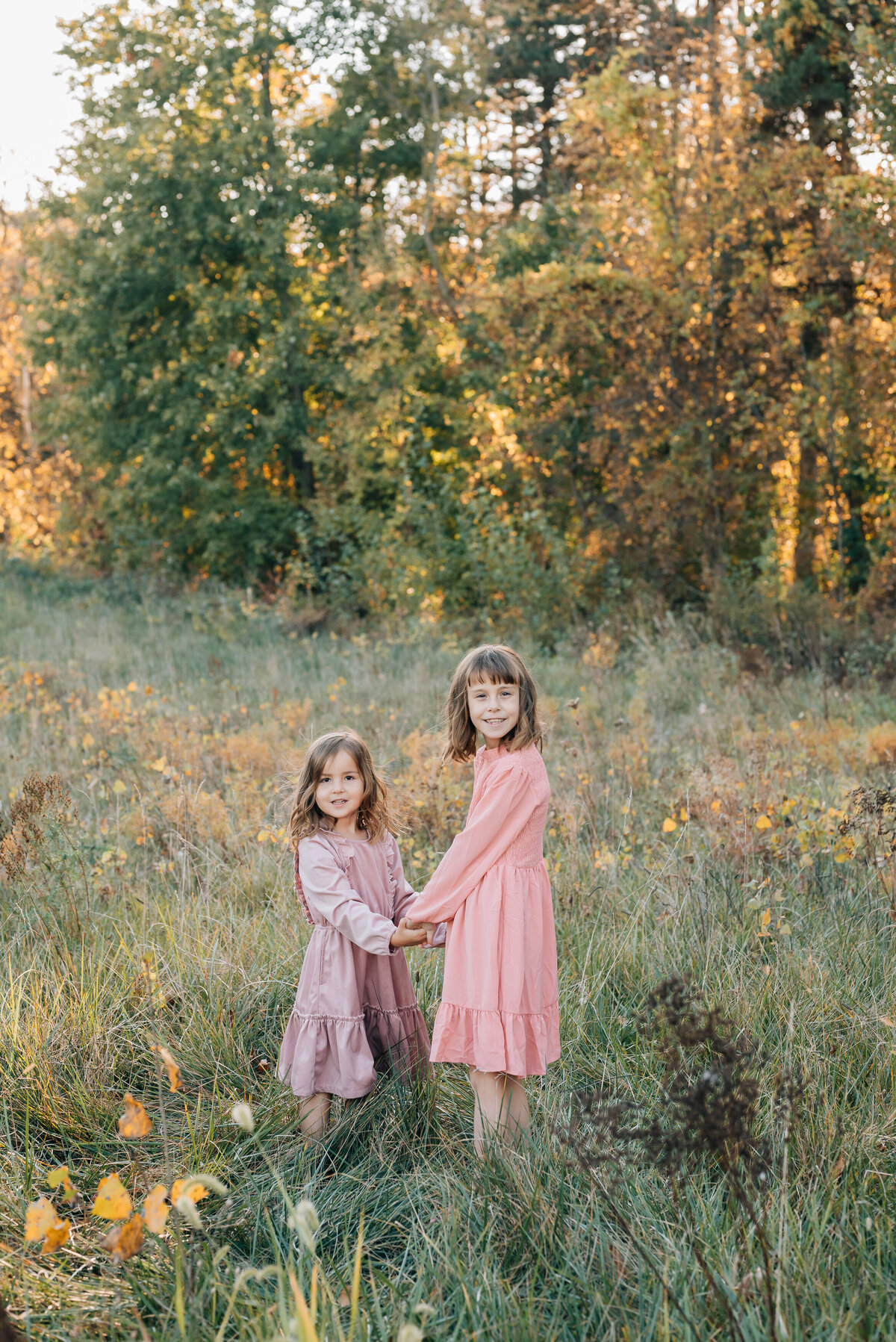 sisters-holding-hands-in-autumn-meadow
