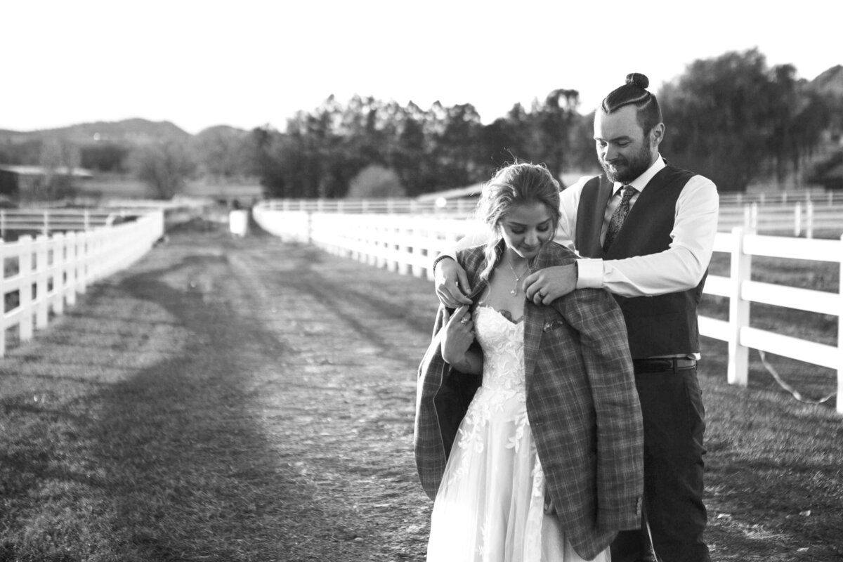 A groom offers his bride his jacket, as they share a sweet embrace,