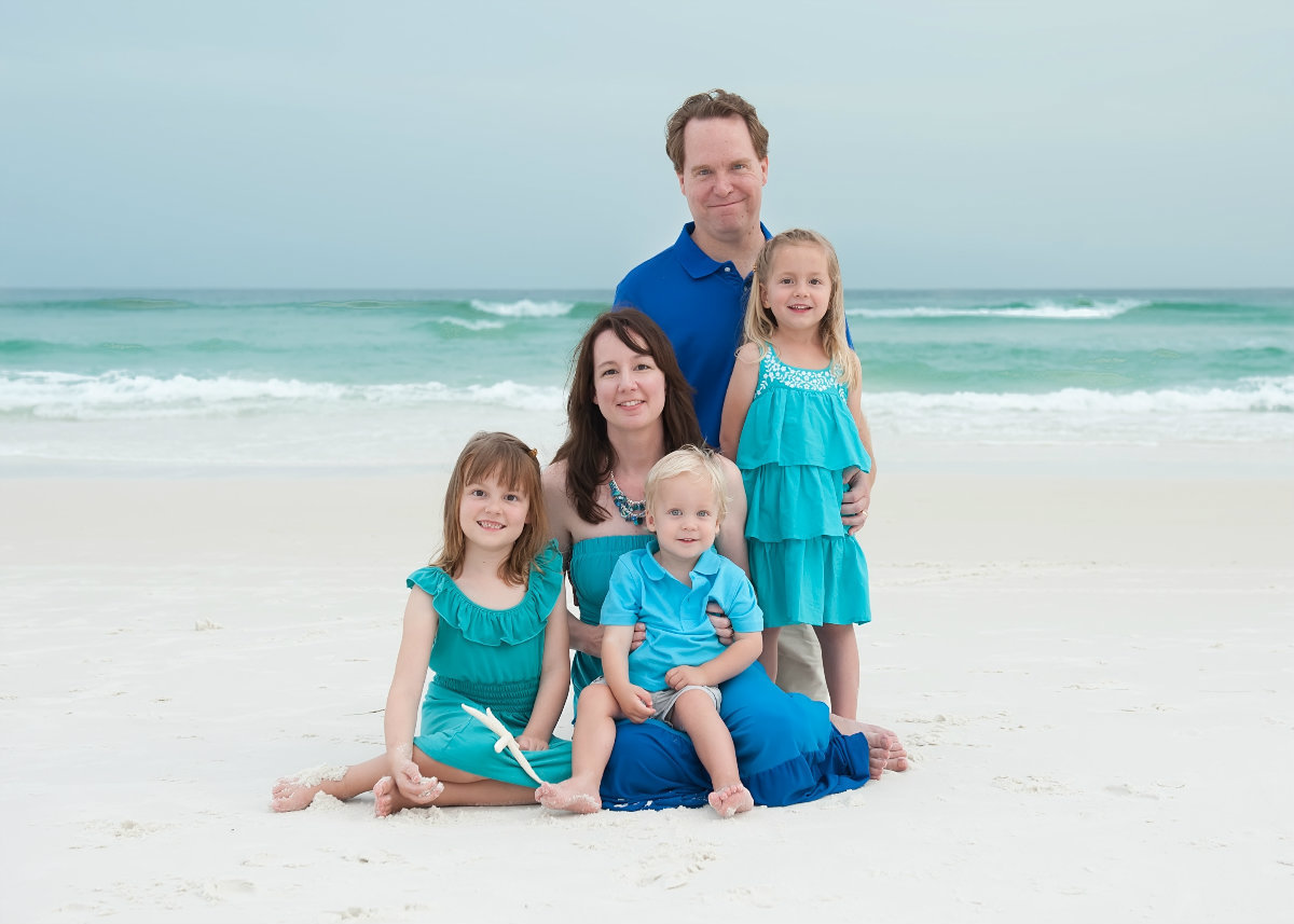 Family dressed in aqua sitting in the sand in Sandestin florida