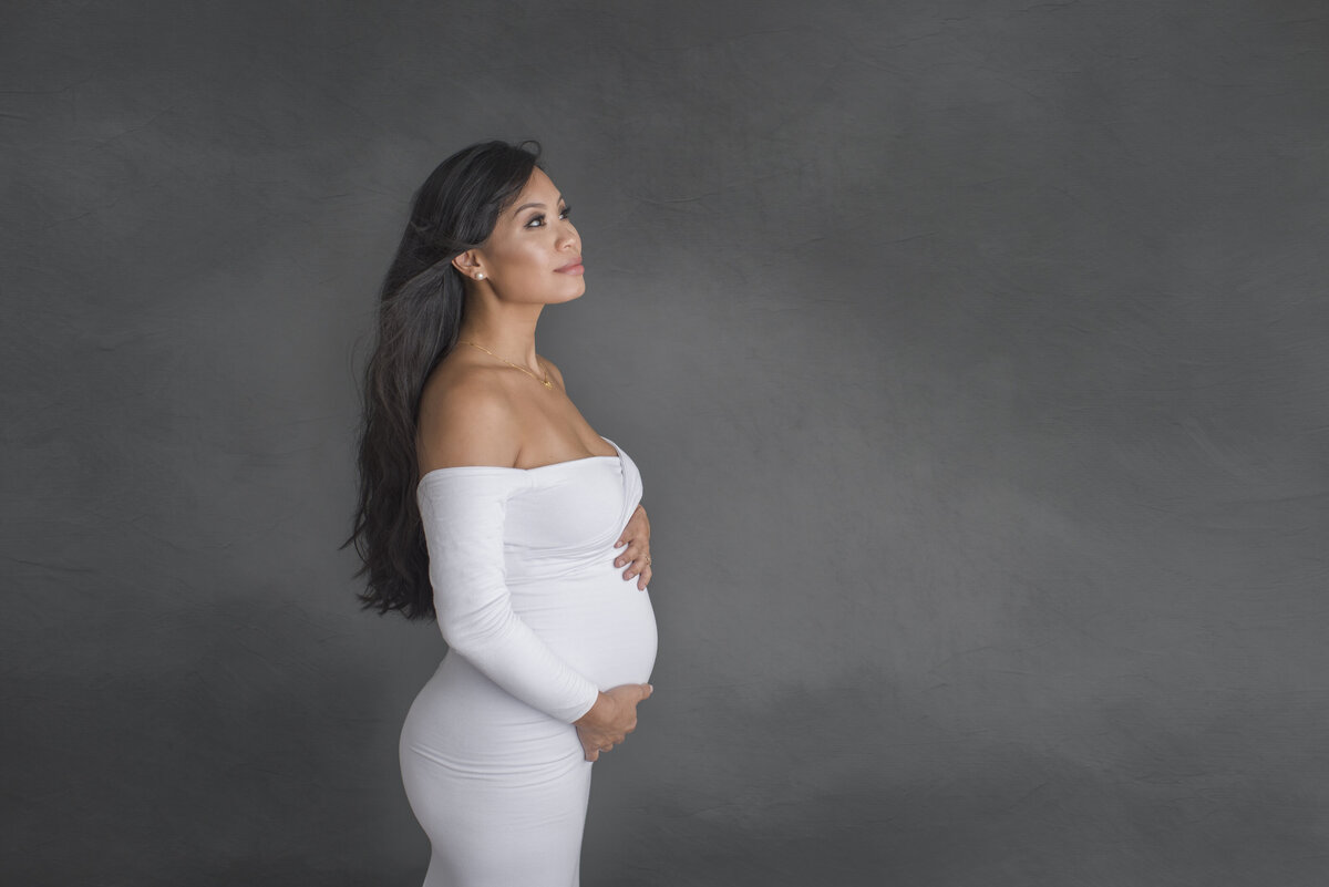 in studio maternity session of lady in tight white dress
