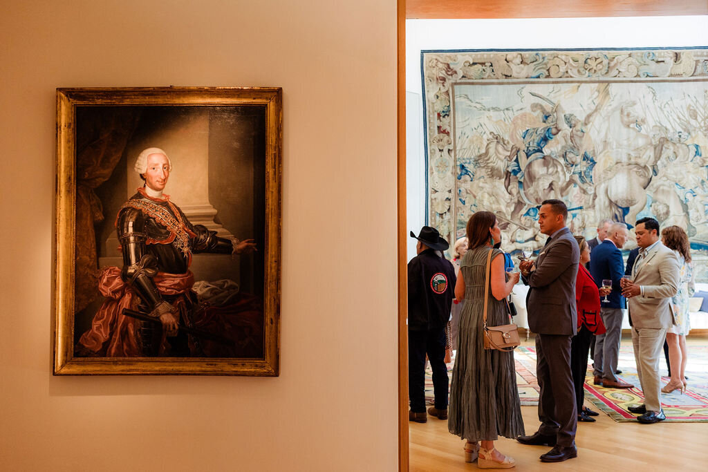 People stand around a room with art.