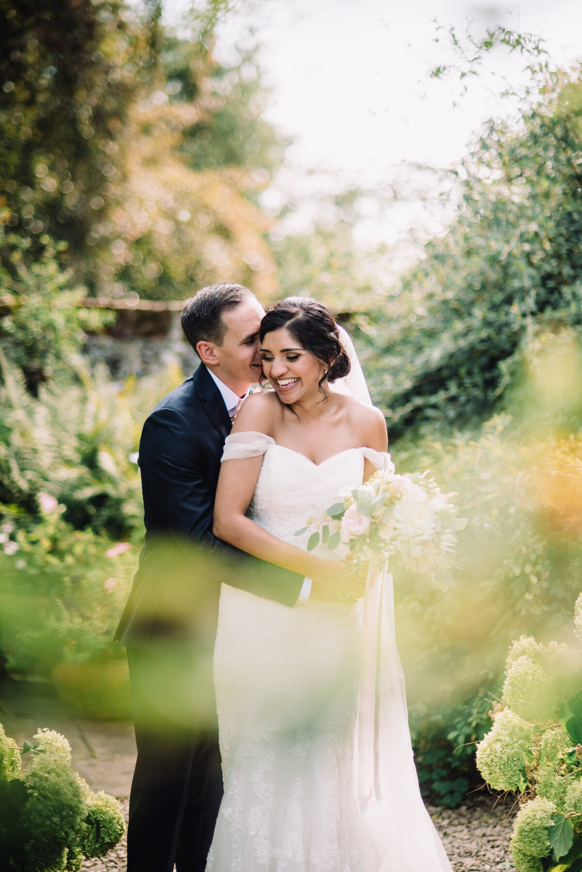 A groom holding his bride from behind whilst they laugh in a woodland area taken by London Wedding Photographer Liberty Pearl