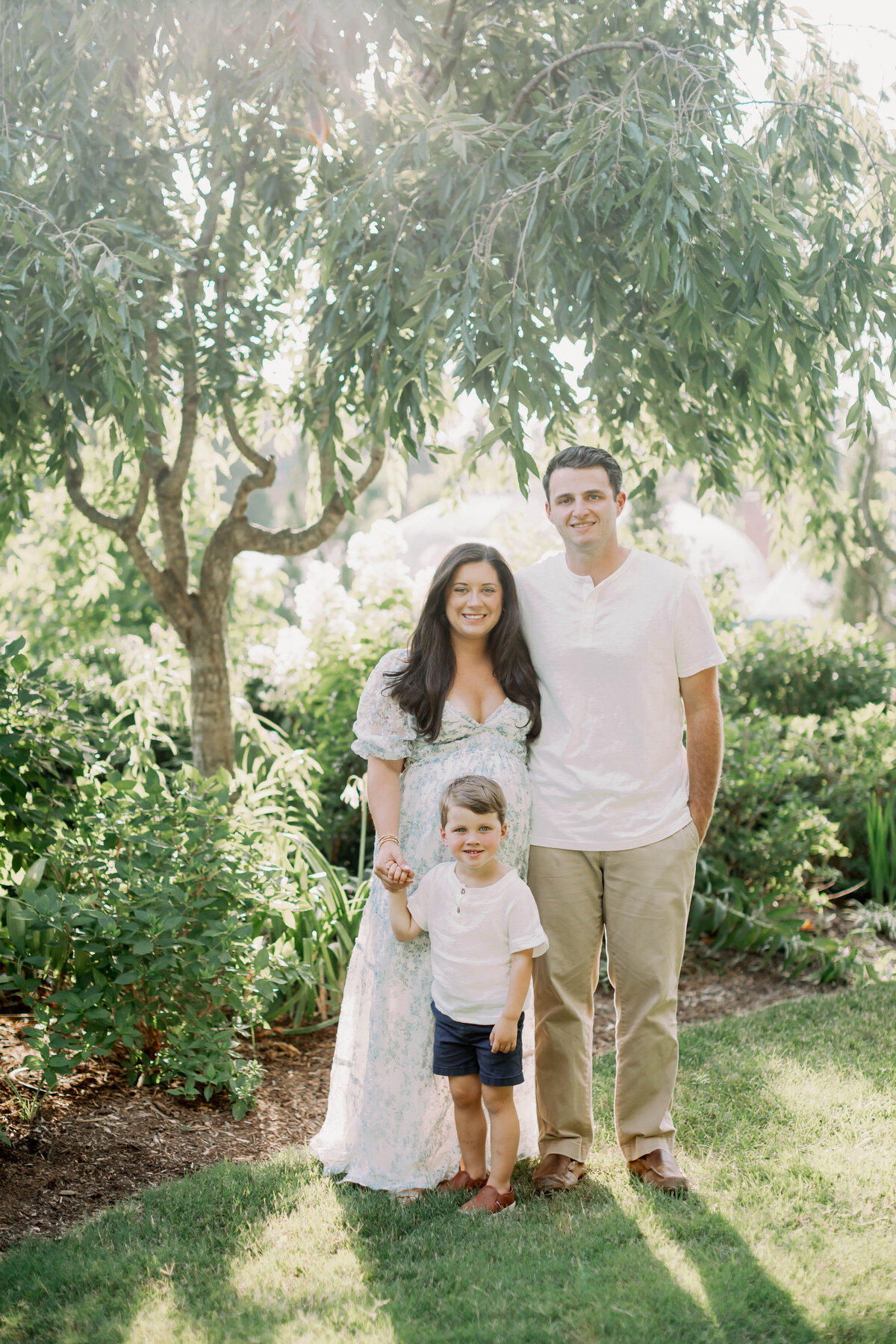 pregnant mom and husband with son in. a garden